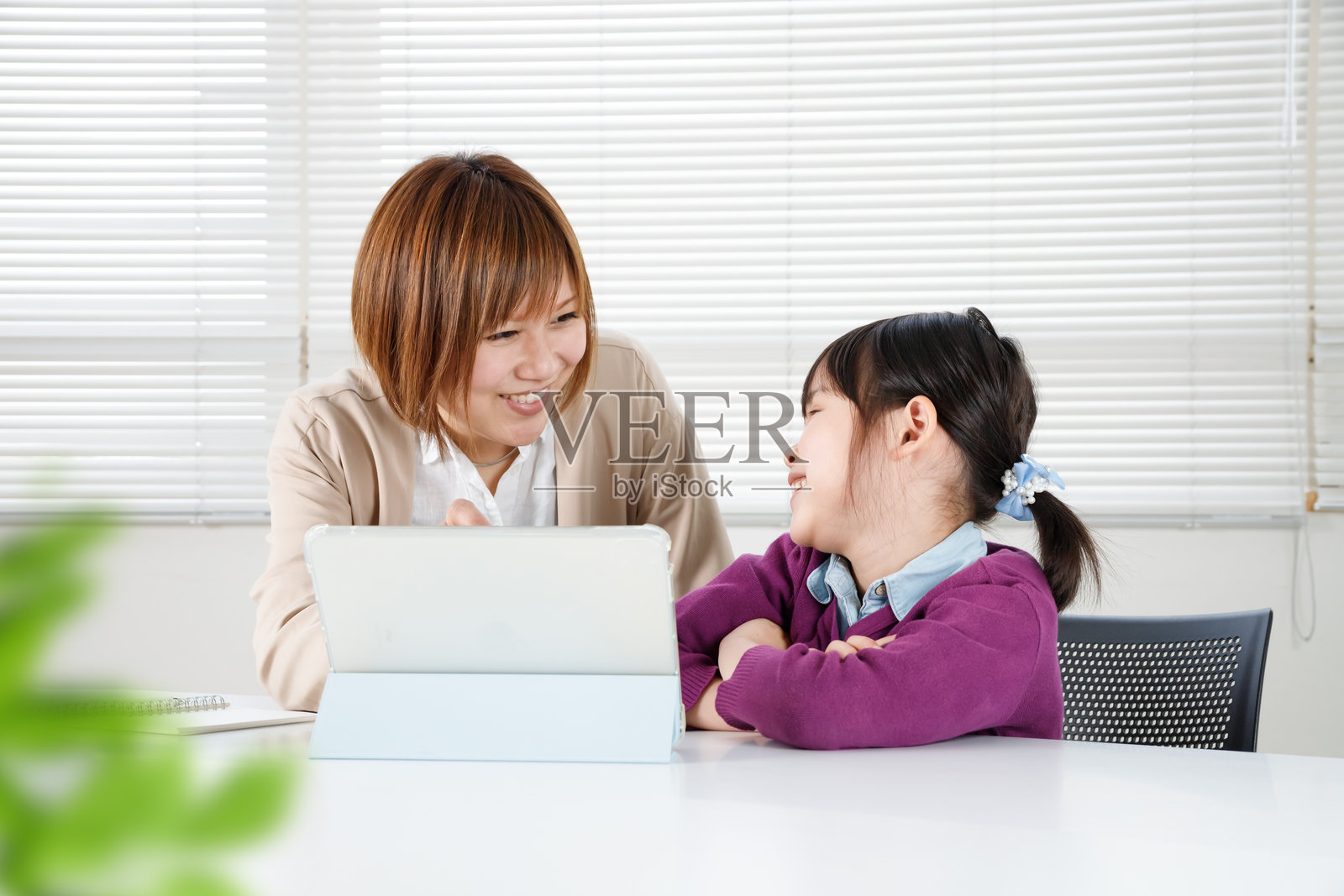 一个孩子高兴地接受表扬,一位日本女性正在用平板电脑教他学习。照片摄影图片