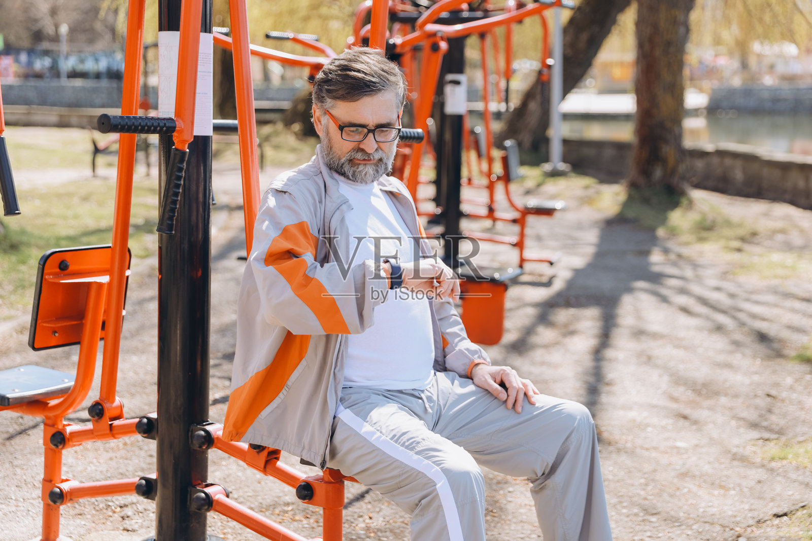 老年男子在户外训练时查看智能手表照片摄影图片