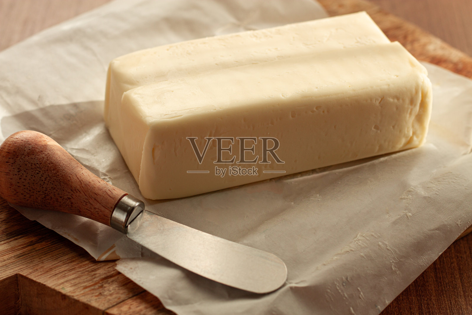 黄油砖,放在包装纸上,木质切菜板和黄油刀,早餐,乡村风格,无人。照片摄影图片