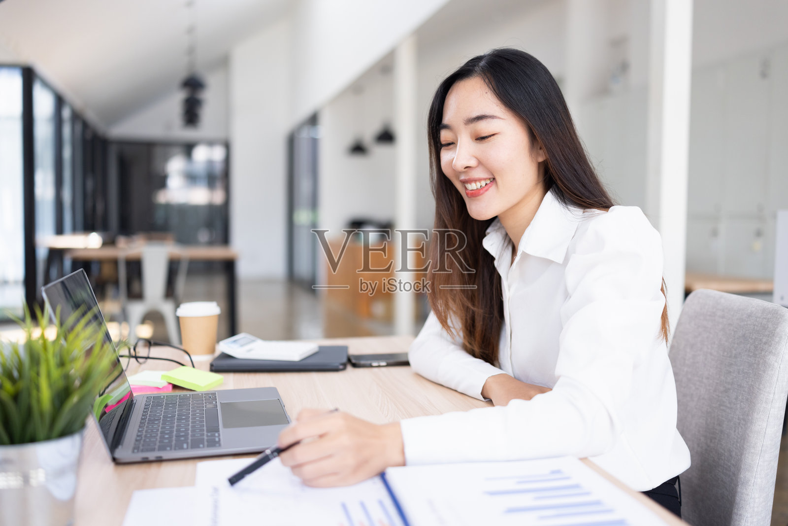 亚洲女商人在办公室工作区的桌子上分析数据。照片摄影图片