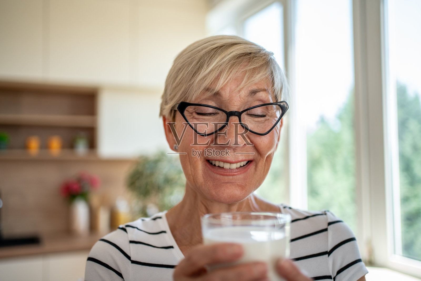 一位年长女性在厨房里享用一杯牛奶照片摄影图片