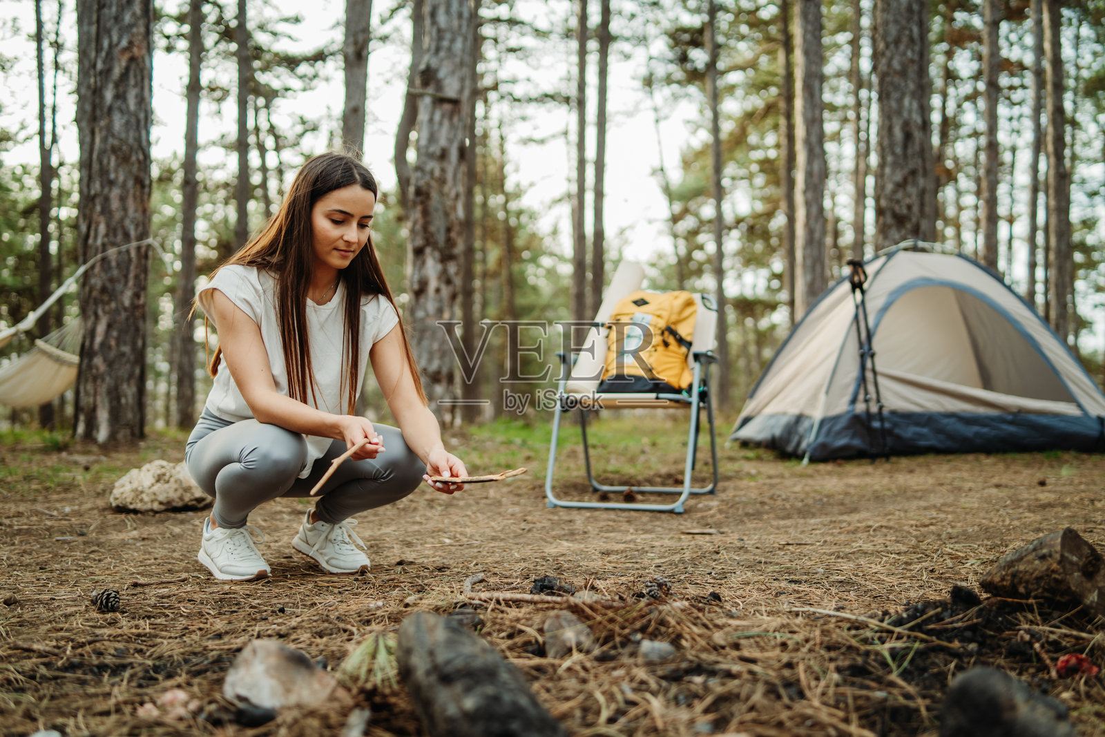 年轻的白人女性在风景如画的森林中为夜晚准备营地和篝火照片摄影图片
