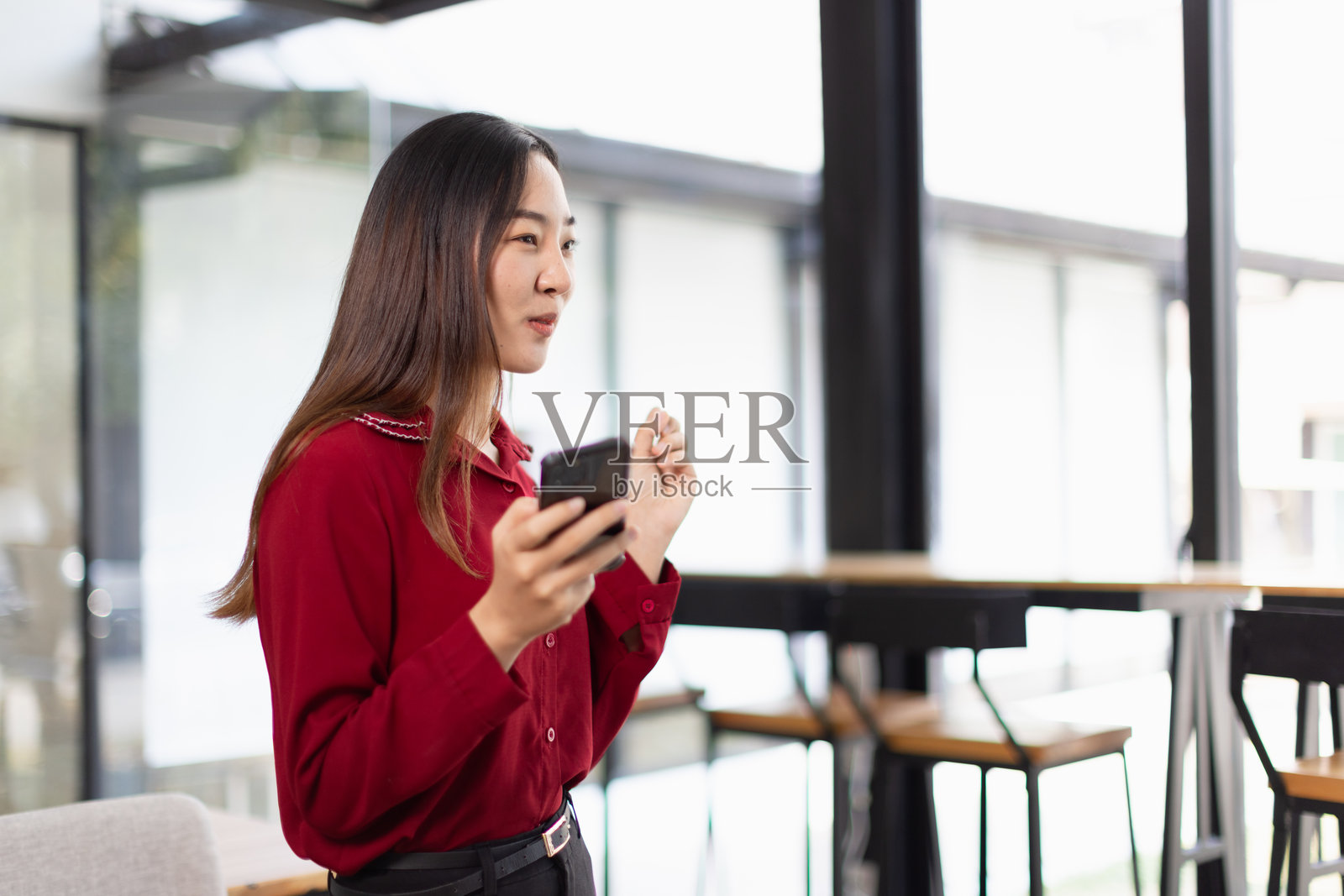 微笑的亚洲年轻女性在办公室使用智能手机,微笑的亚洲女性。照片摄影图片