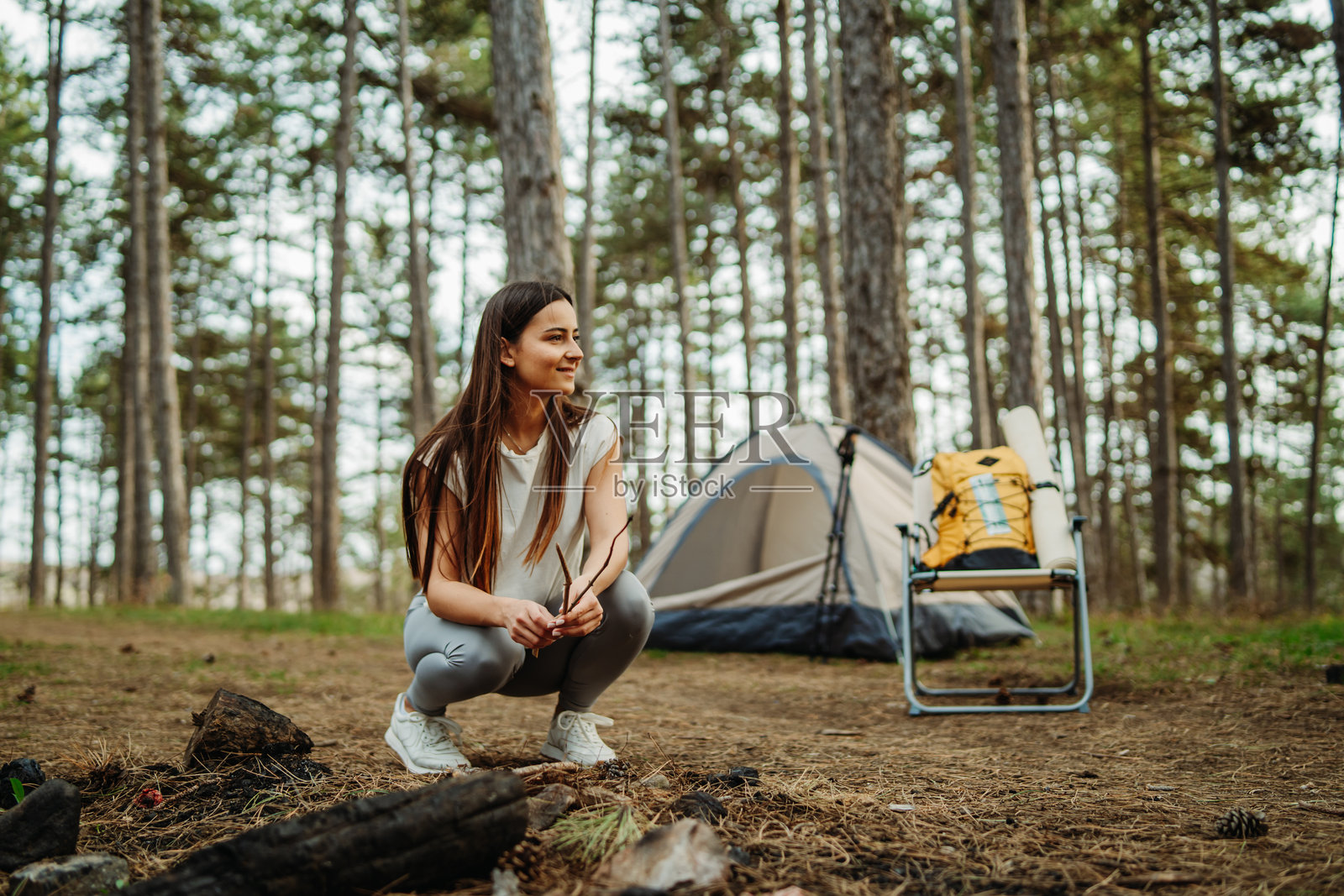 年轻的白人女性在风景如画的森林中为夜晚准备营地和篝火照片摄影图片