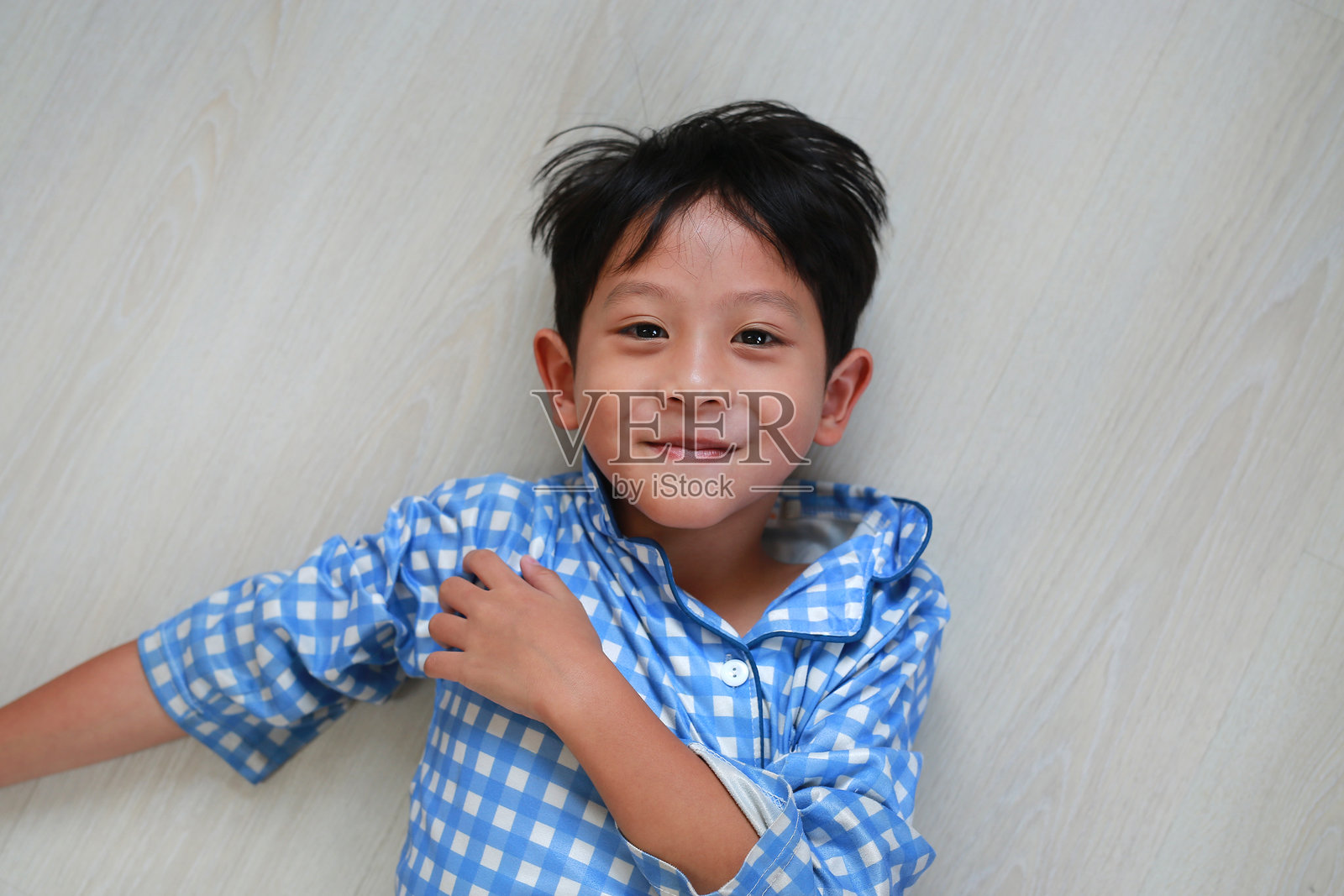 快乐的亚洲男孩躺在地板上,面朝镜头,特写镜头。照片摄影图片