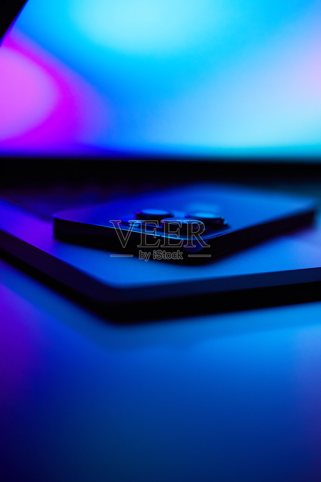 带有智能手机的笔记本电脑。霓虹暗光。照片摄影图片