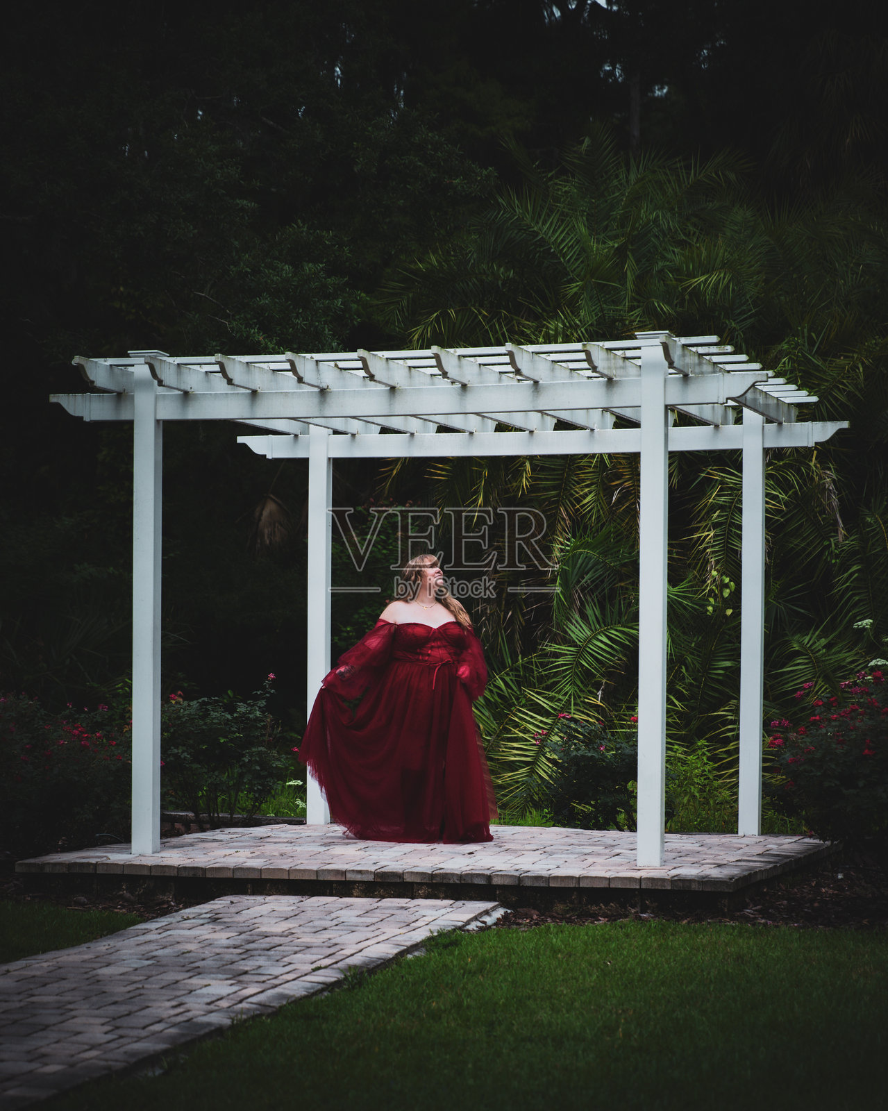 穿着红色连衣裙的女人在凉亭中照片摄影图片