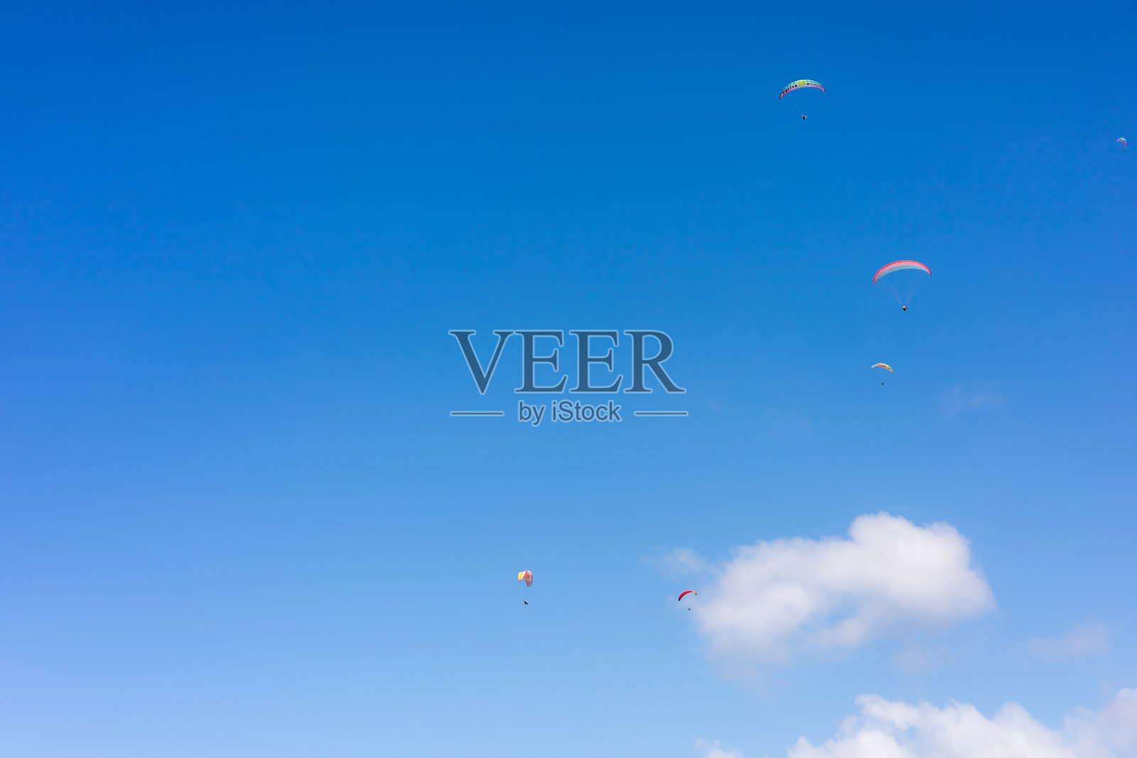 在阳光明媚的下午,滑翔伞在湛蓝的天空中翱翔照片摄影图片