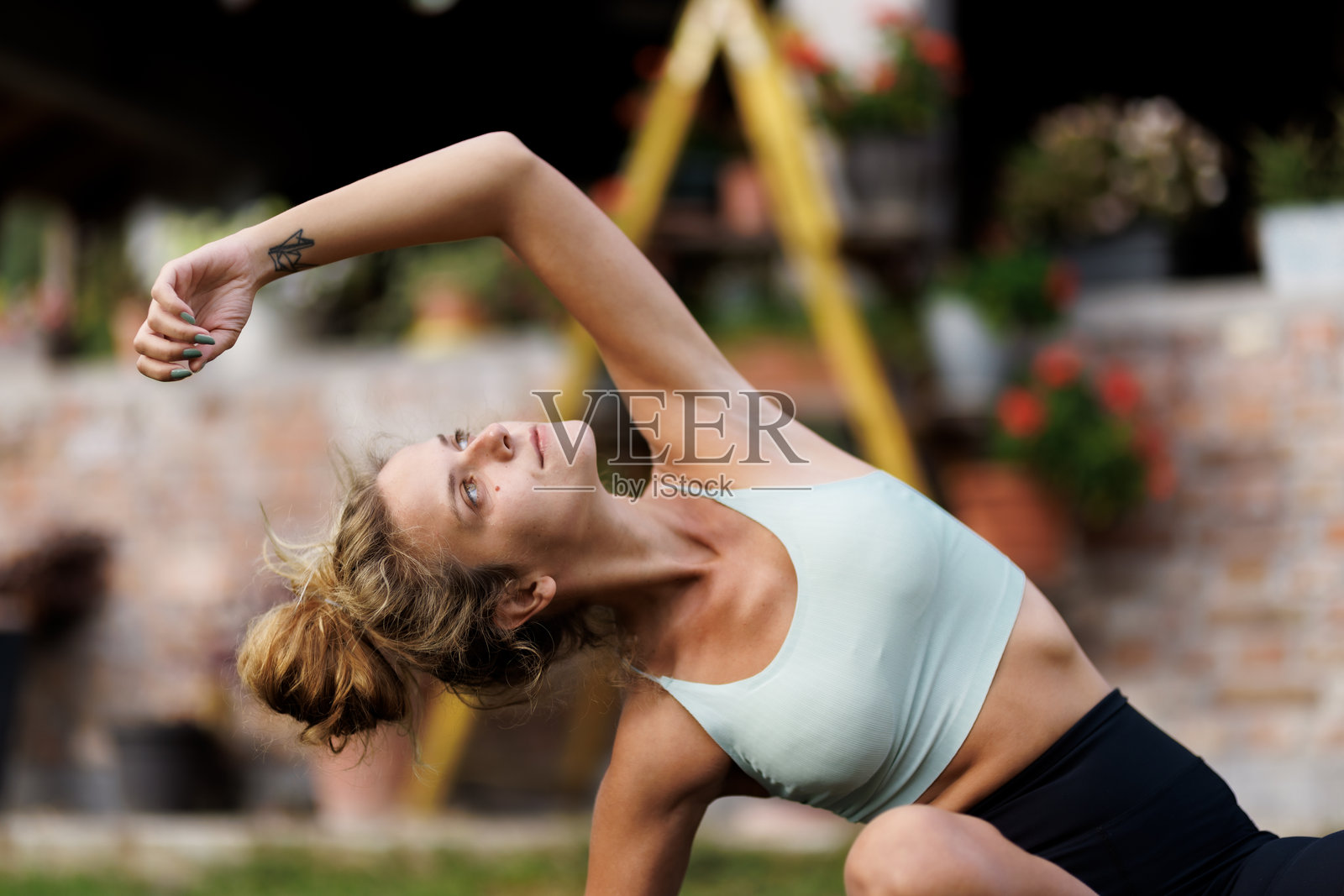 一位美丽的女性在户外花园环境中进行瑜伽练习,正值白天。照片摄影图片