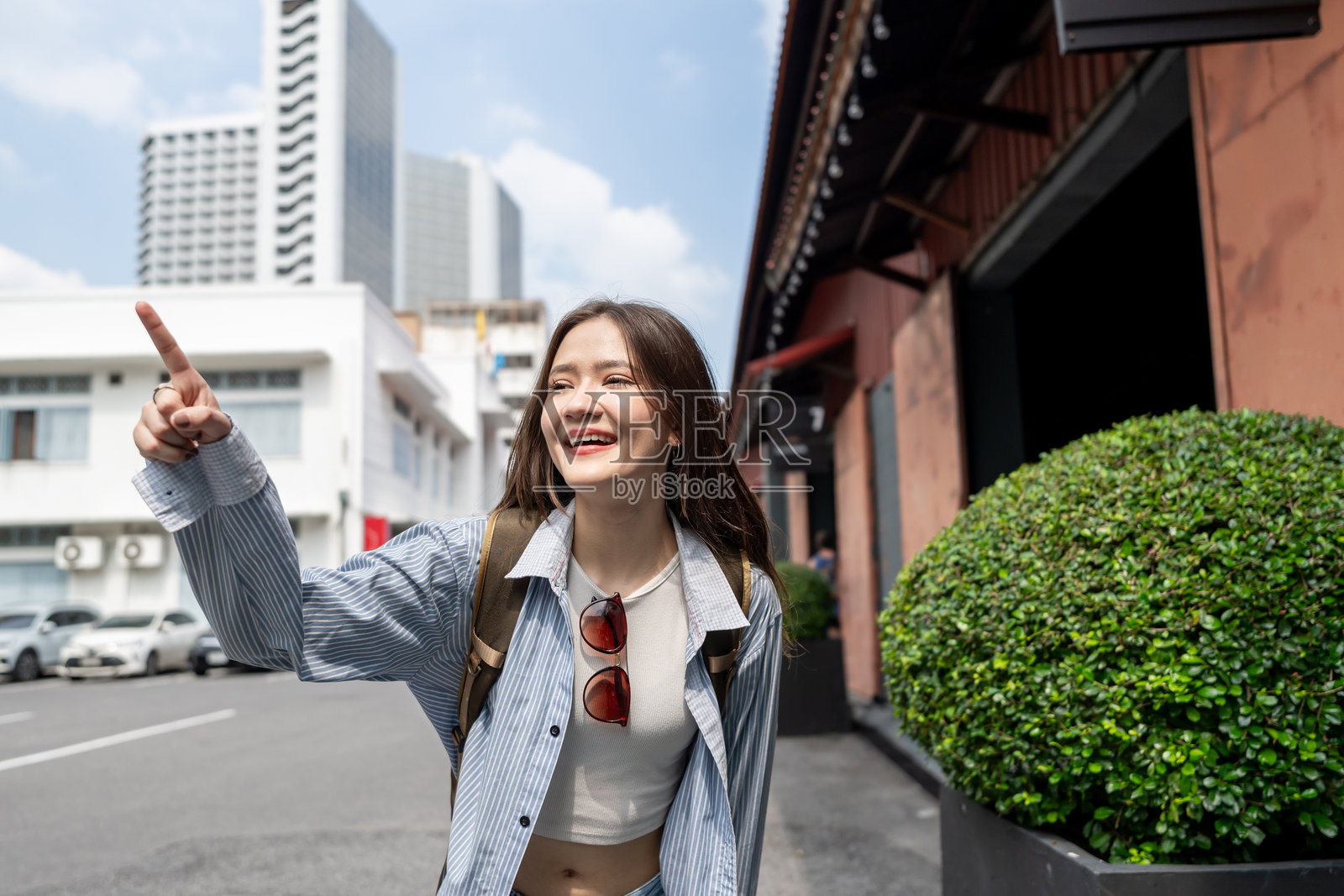 年轻美丽的亚洲女性背包客在户外探索城市。迷人的女性旅行者感到快乐和放松,享受在街道上漫步,度过假期的闲暇时光。照片摄影图片