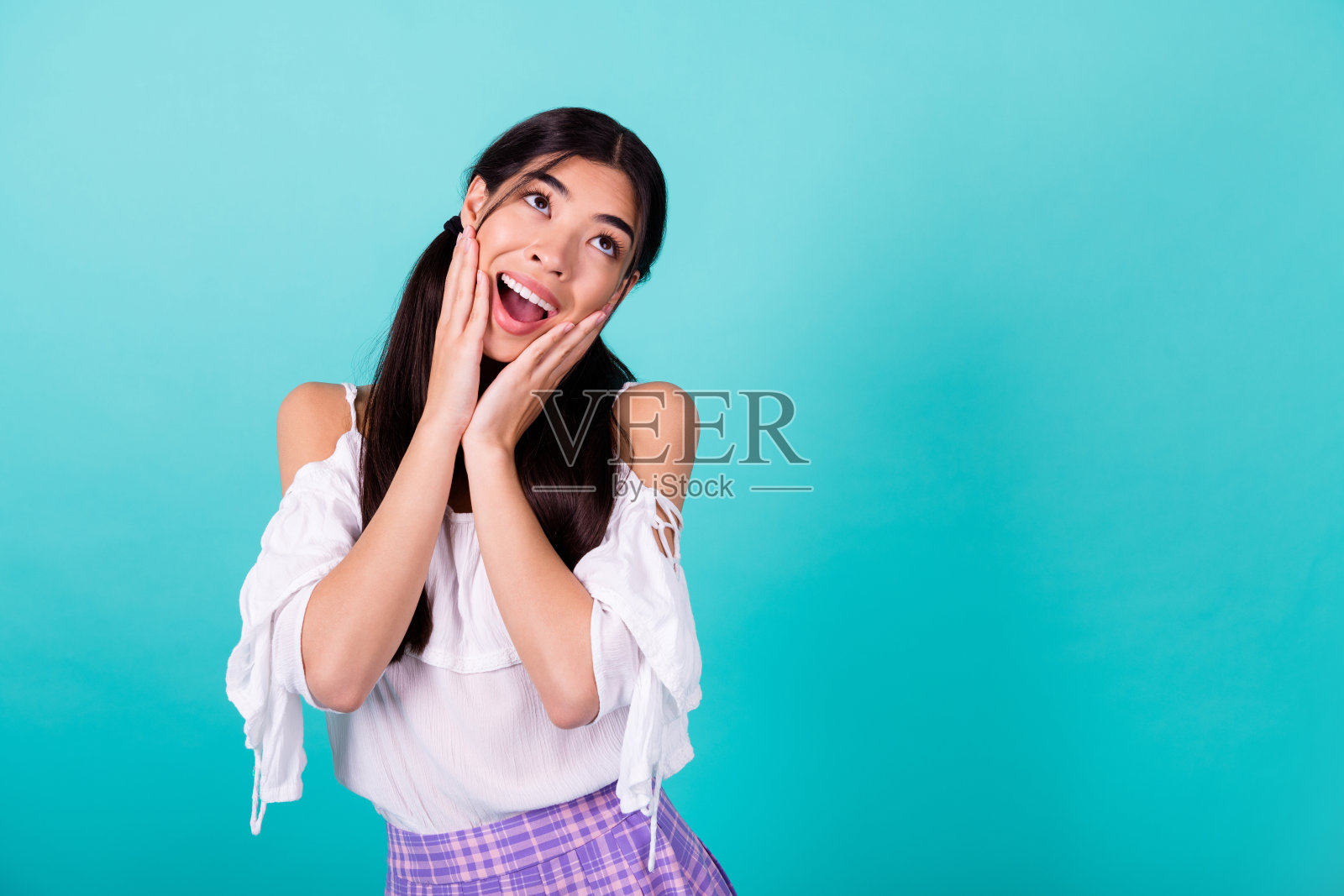 一个印象深刻的积极人士双手托着脸颊,凝视着空旷的空间,背景为翡翠色。照片摄影图片