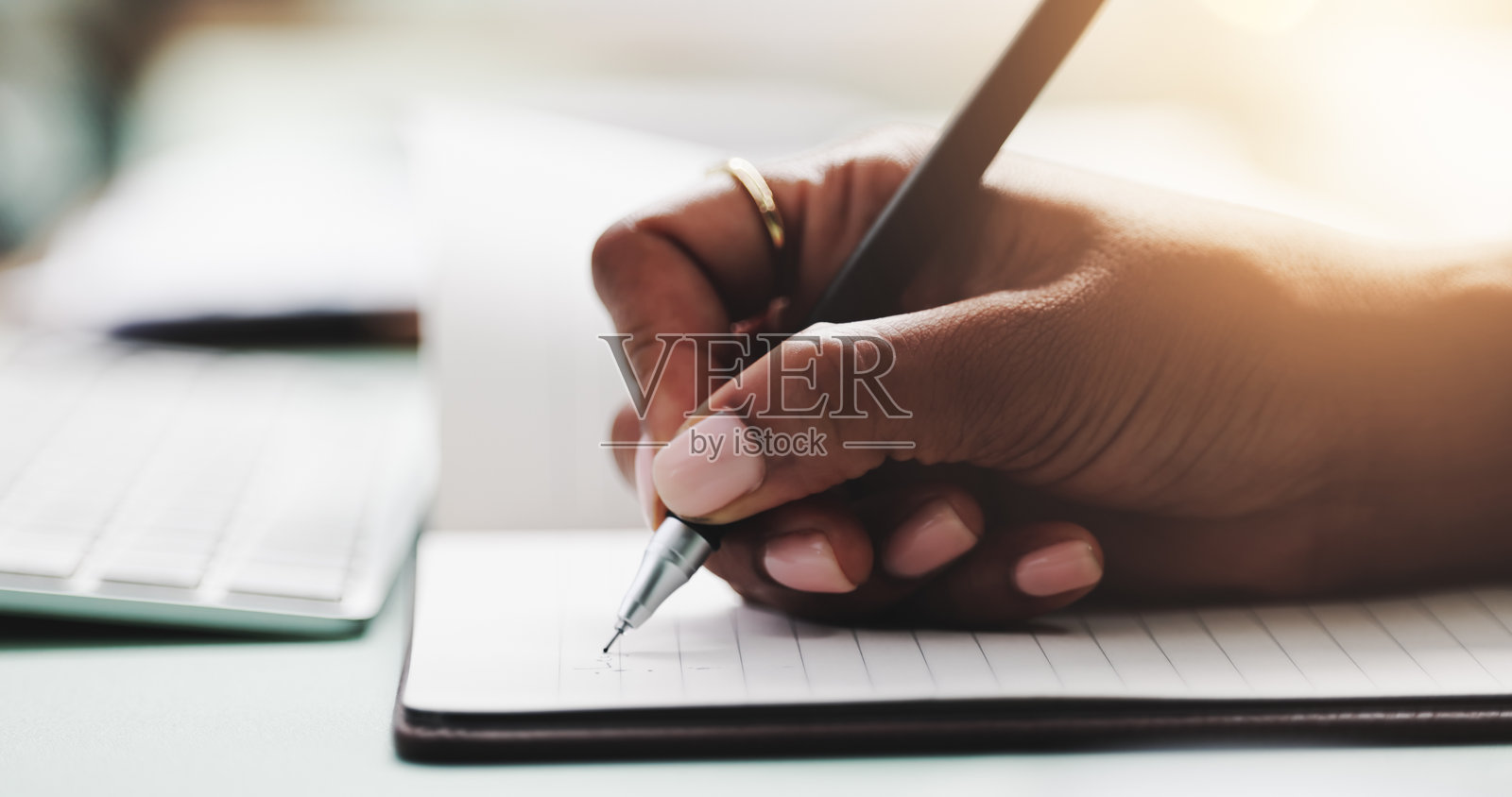 办公桌上的商务人士手握笔记本,进行议程、计划或日程安排的书写。工作场所中员工的日记、日志或计划本特写,记录约会或创意。照片摄影图片