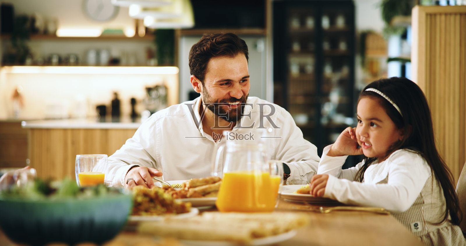 快乐的父亲和孩子在家享用午餐,健康的餐点和丰盛的美食增进亲子关系。微笑的男人和女孩一起享用营养丰富的早餐和家庭聚餐。照片摄影图片