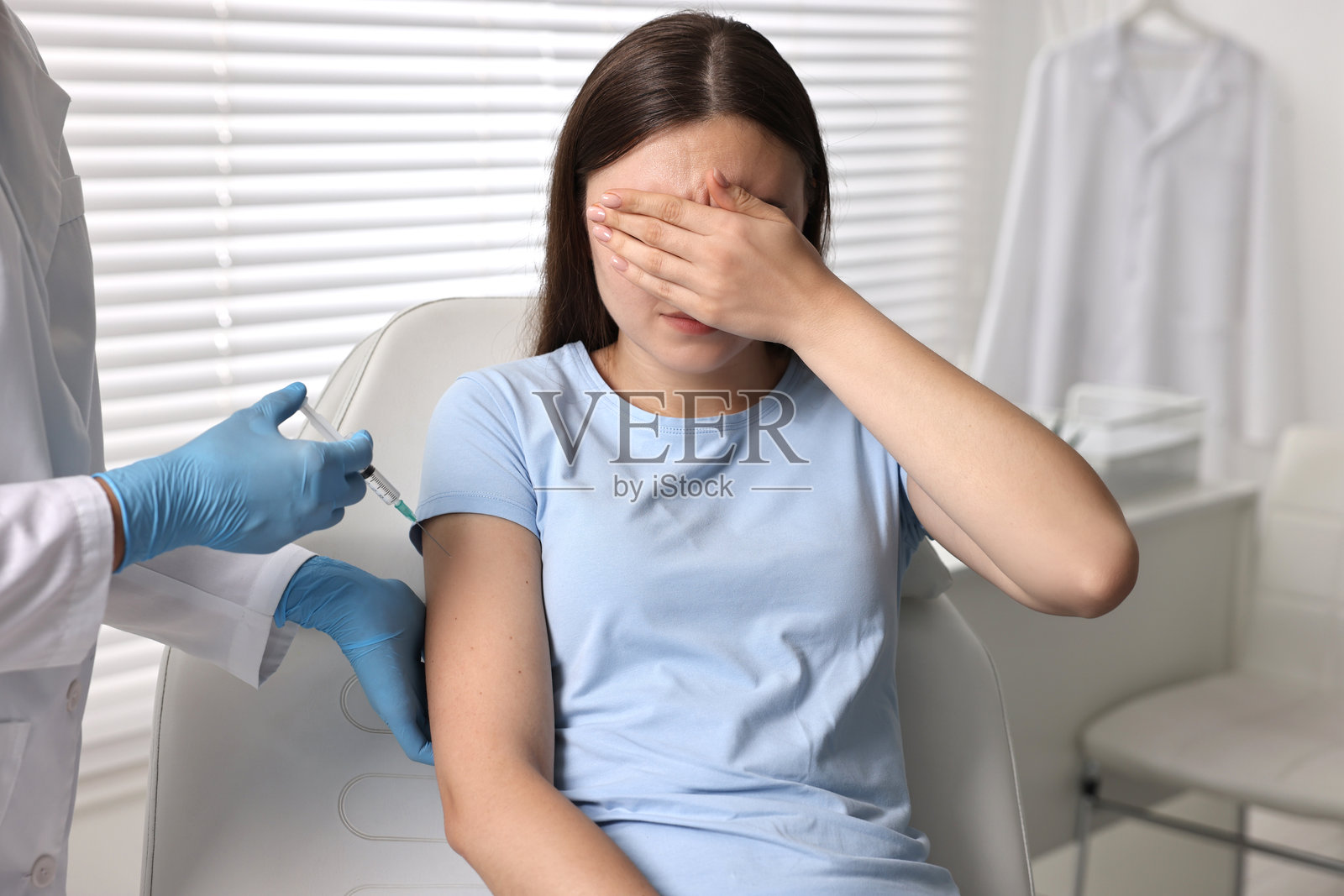 牙科恐惧症。牙医在诊所里用注射器靠近害怕的女性,特写镜头照片摄影图片