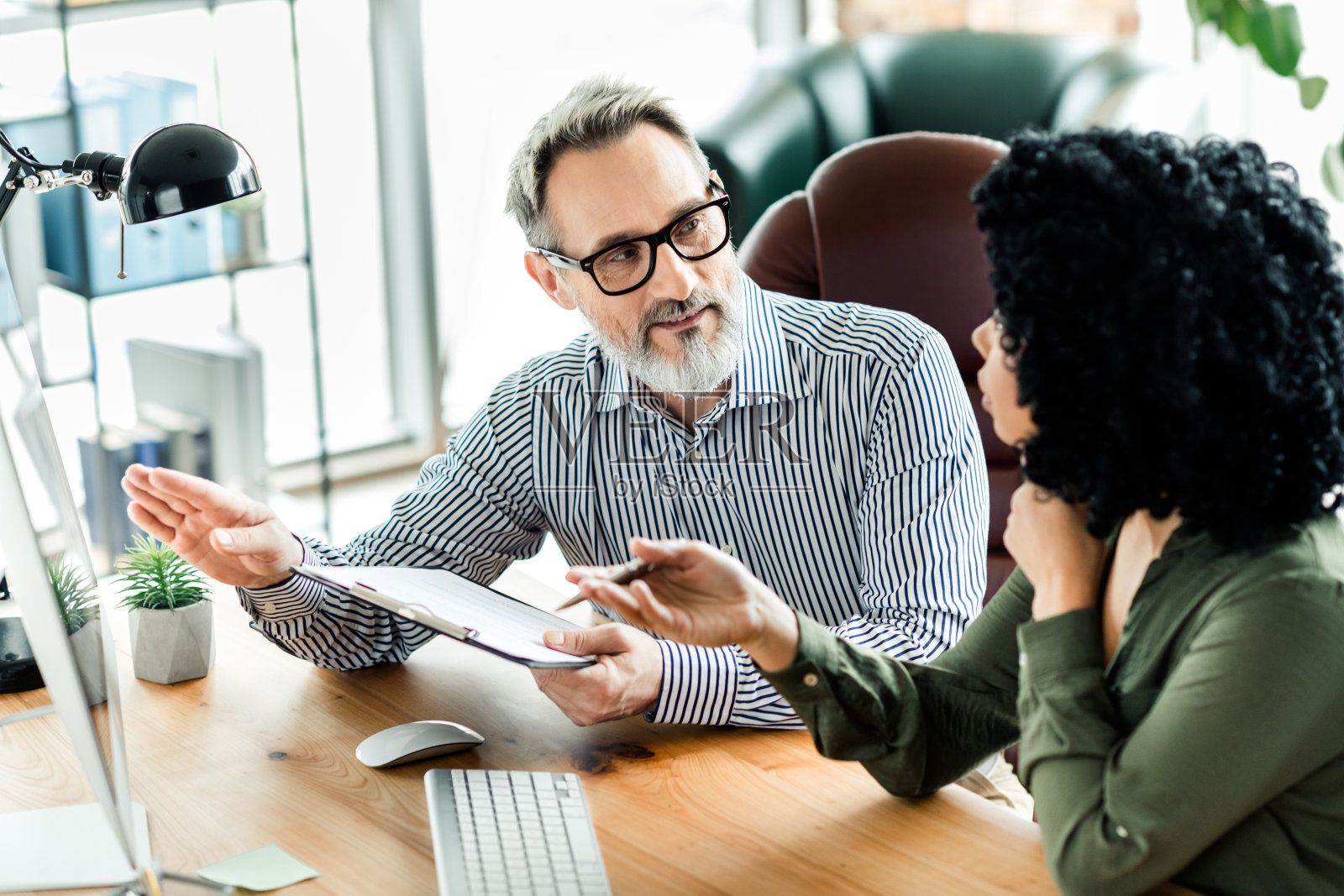 成熟的职业男性与年轻女性在现代企业办公室环境中讨论项目照片摄影图片