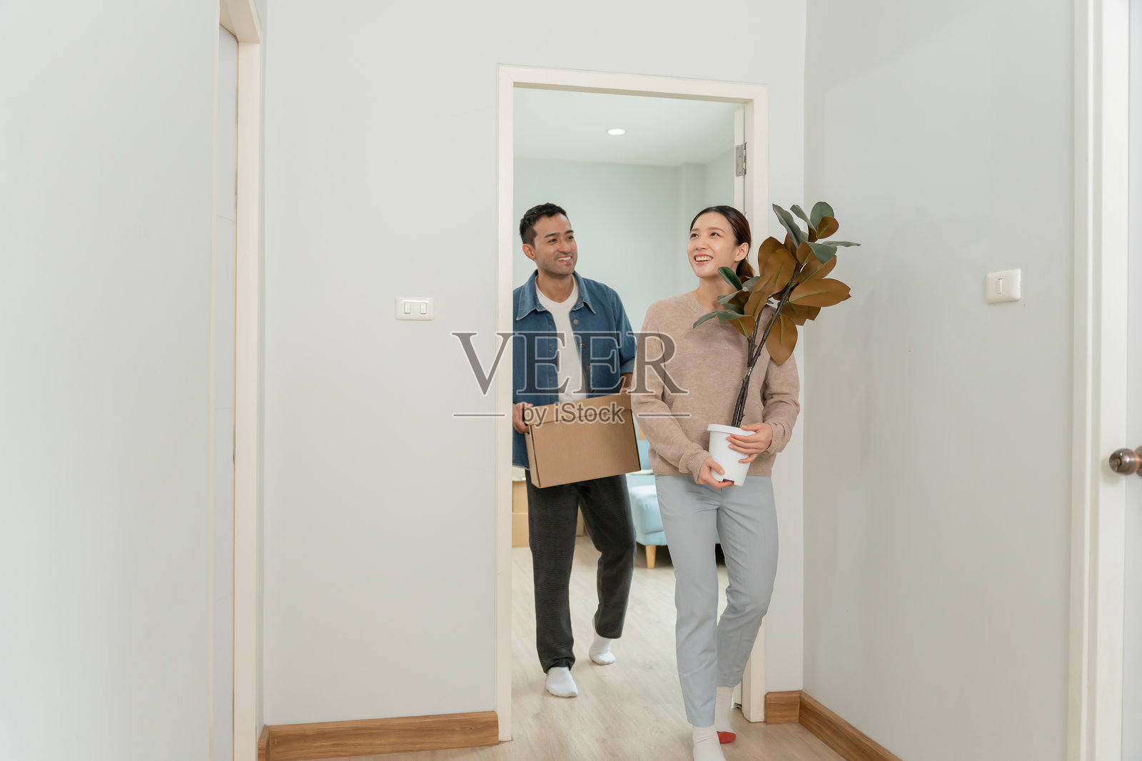 搬家,迁移。情侣们手持装有新公寓设备的纸箱,房间内有一个装有个人物品和家具的纸箱。搬进公寓。照片摄影图片