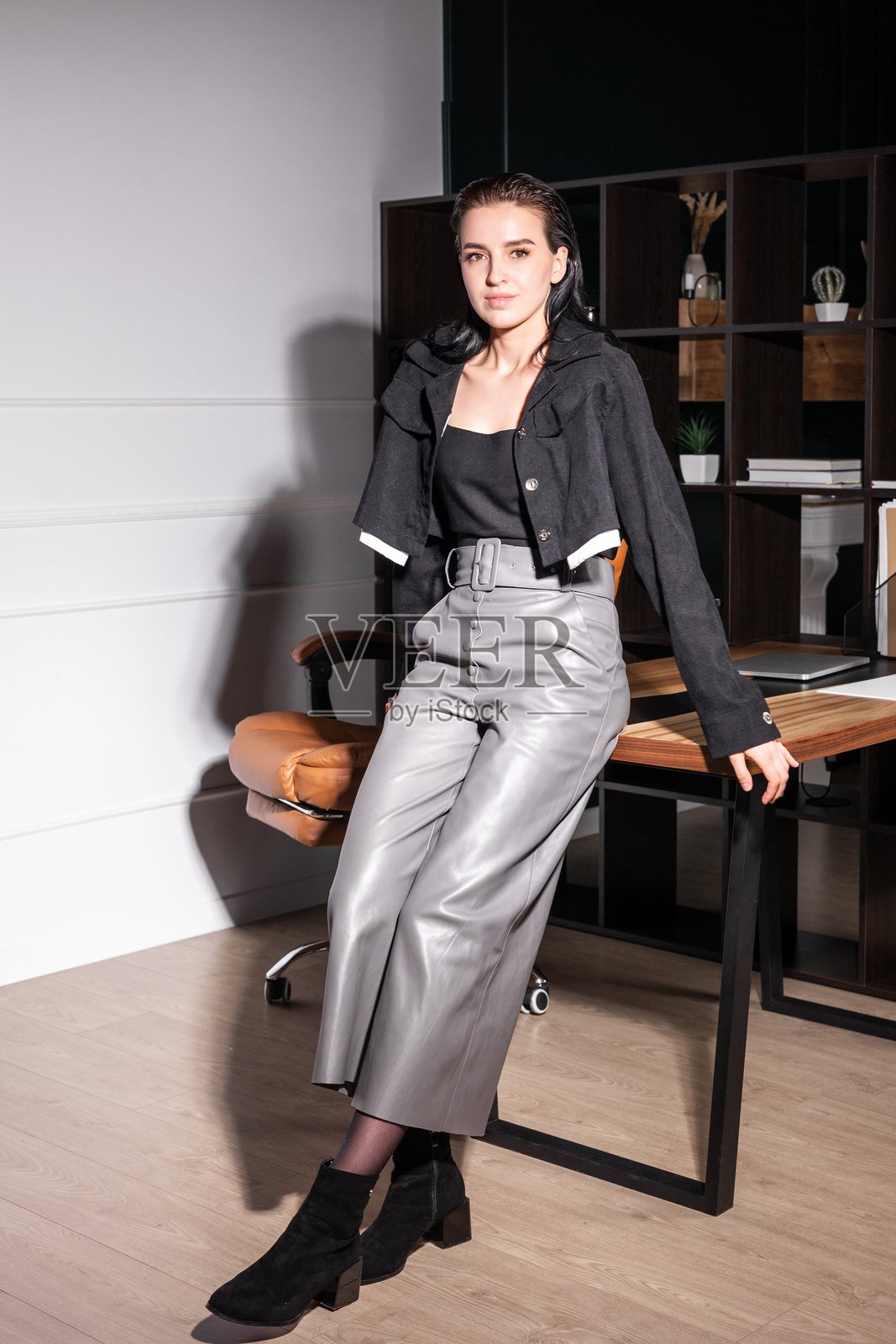时尚年轻女性在现代办公室环境中自信地摆姿势,穿着时尚服装和靓丽鞋履。照片摄影图片