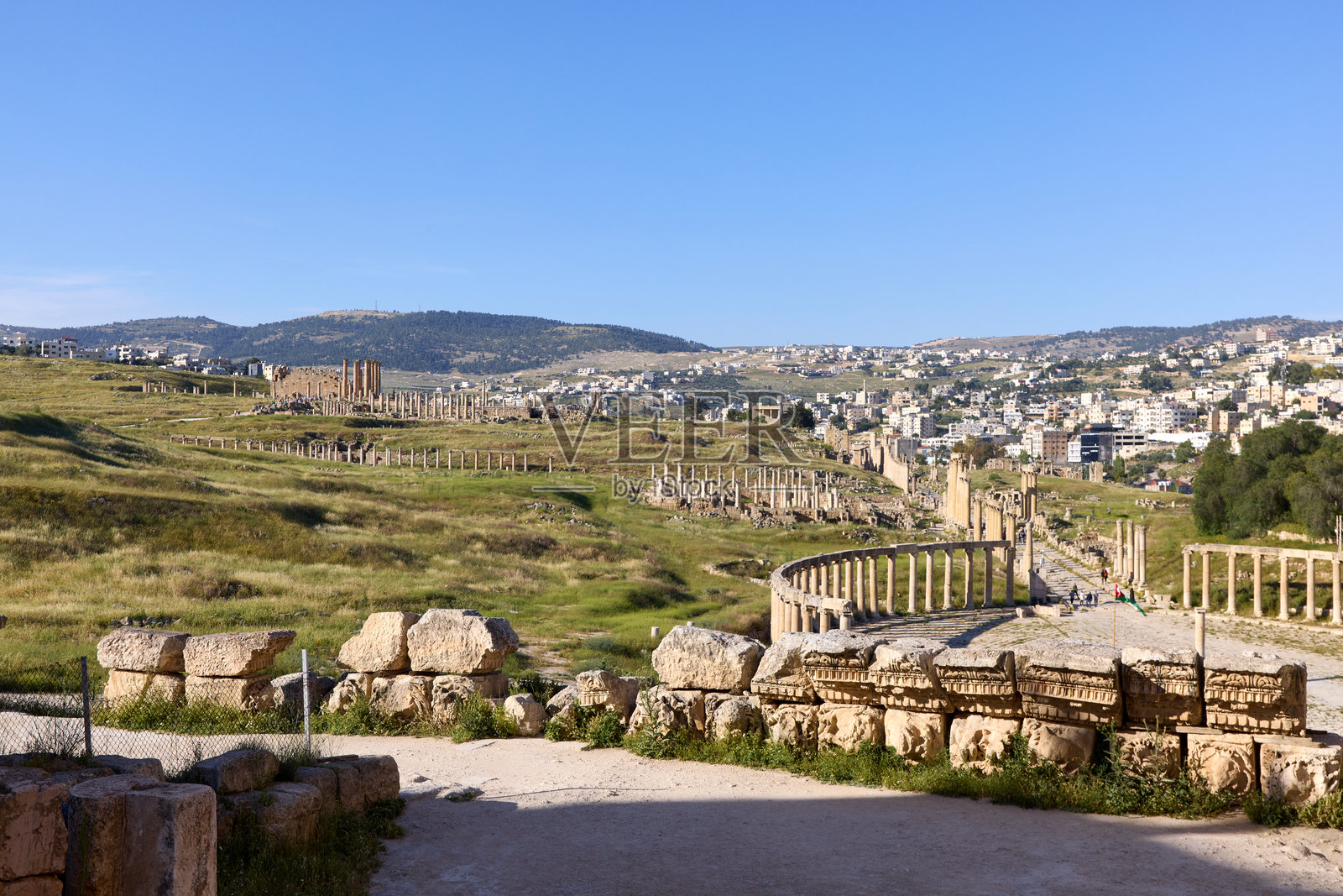 游客们在约旦的杰拉什古遗址探险,欣赏保存完好的罗马遗迹、柱子以及环绕历史城市的郁郁葱葱的绿地。照片摄影图片