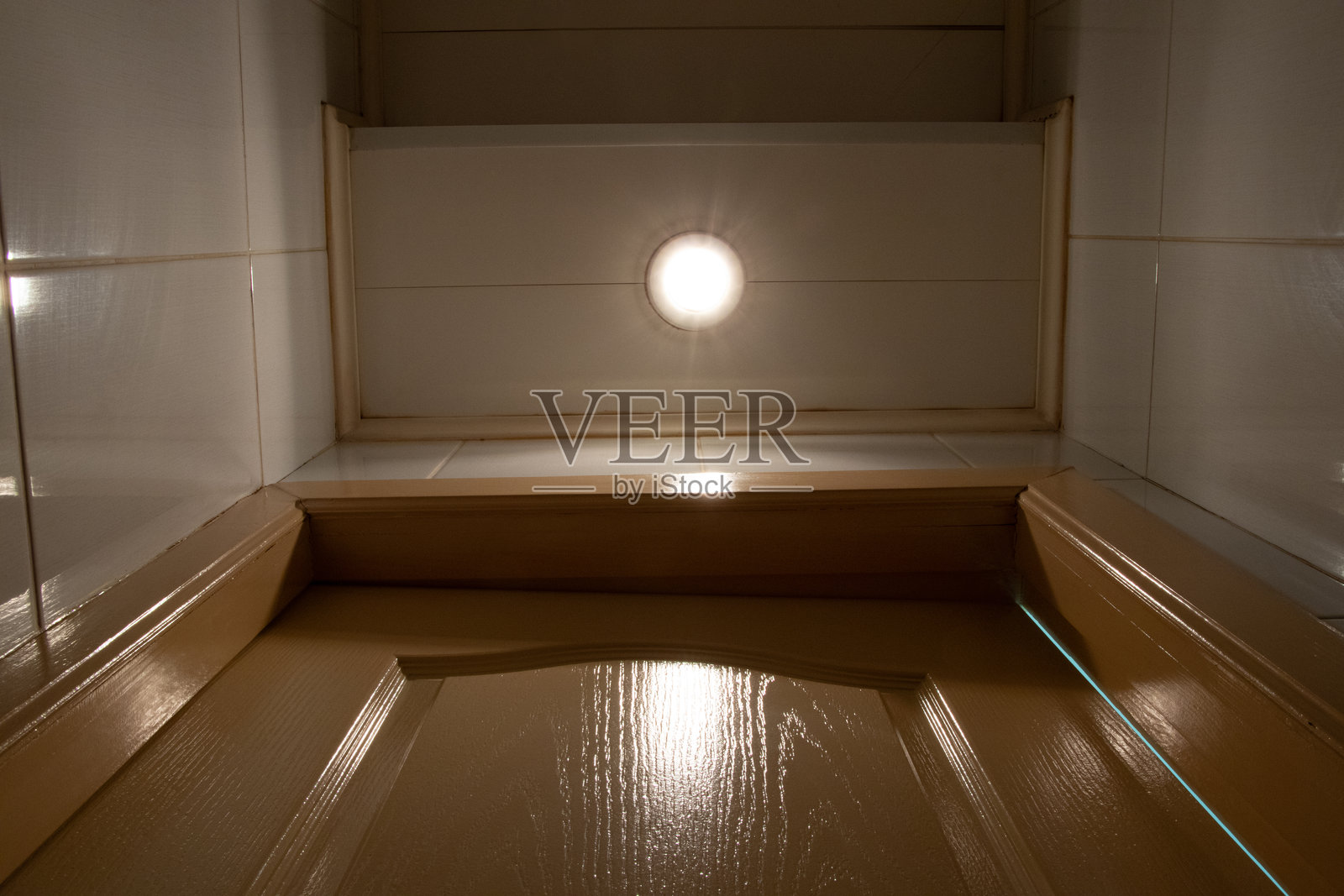 从底部向上看一扇关闭的浴室门,天花板灯亮着,厕所在旁照片摄影图片