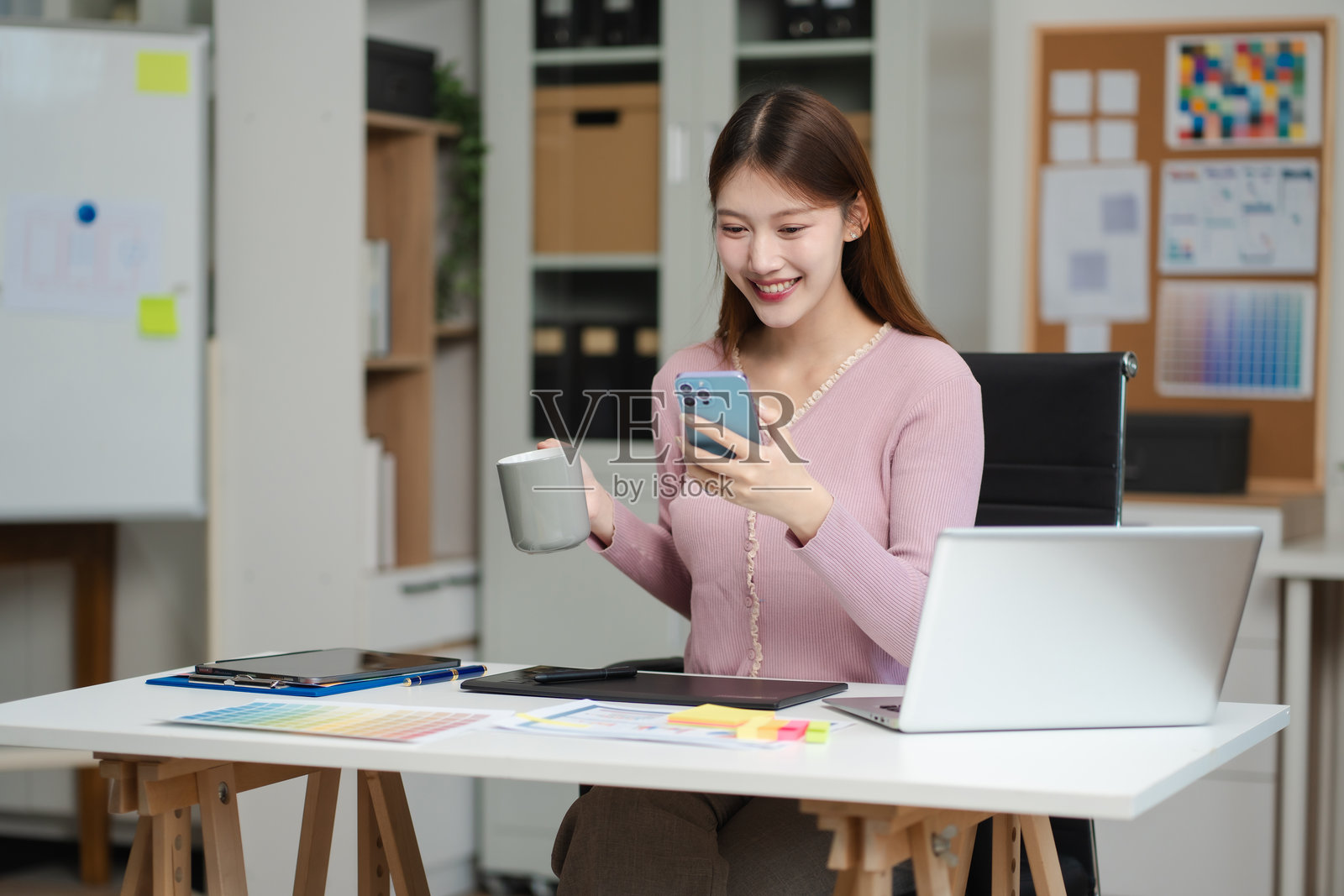 女性程序员或开发者在工作场所使用智能手机和电脑屏幕进行问题解决。照片摄影图片