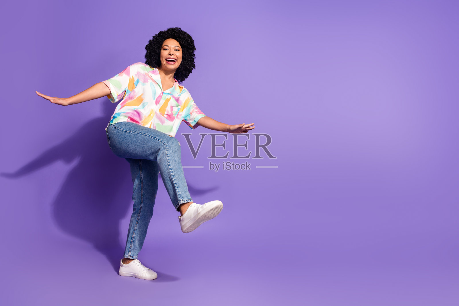 穿着色彩缤纷夏季服装的快乐年轻女性在紫色背景前俏皮地做手势,展现充满活力的生活方式和时尚。照片摄影图片