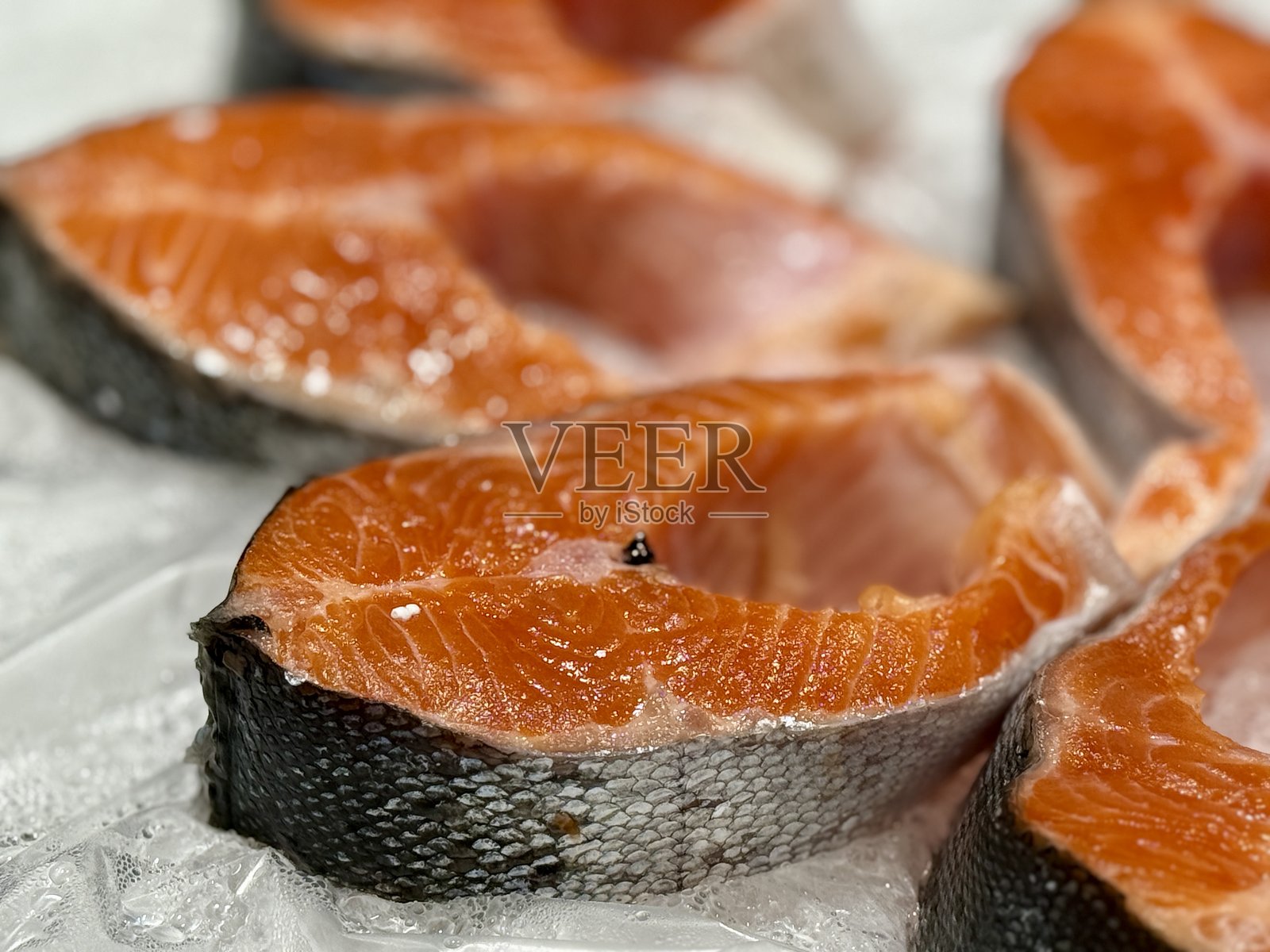 超市出售的冷冻生材料制成的冷冻大西洋鲑鱼牛排,特写镜头。照片摄影图片