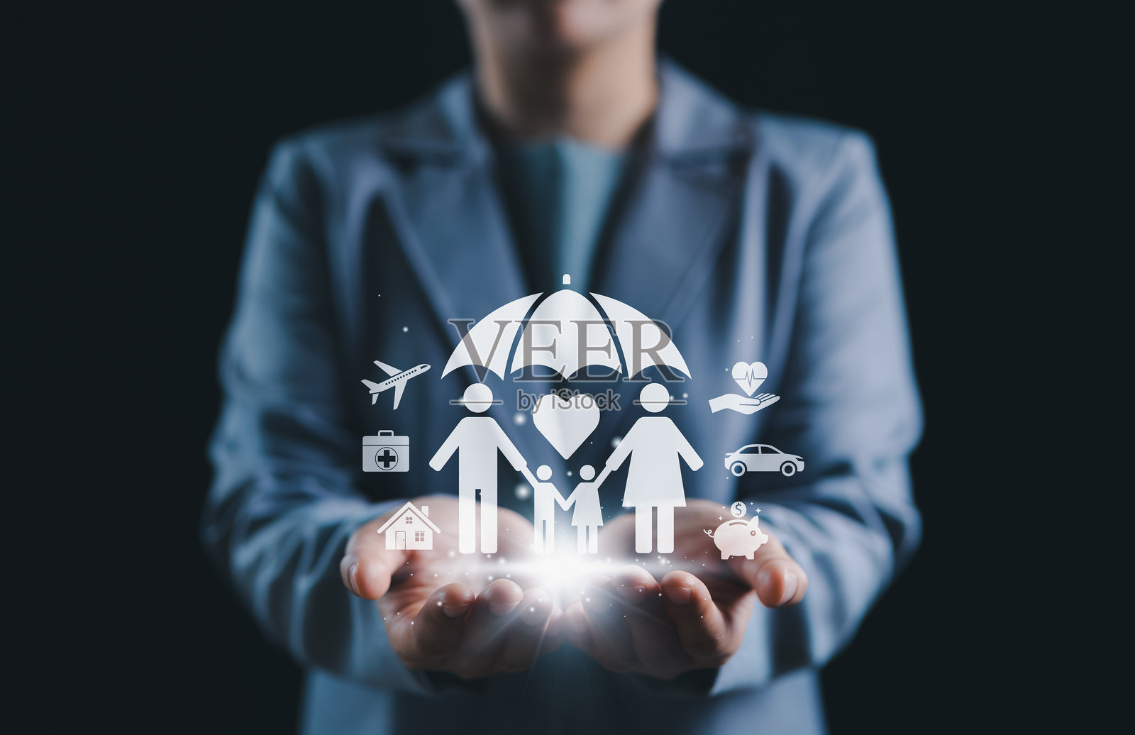 家庭保护与保险概念。一个人手持发光的数字图标,象征着家庭在伞下的生活、健康、汽车、房屋和旅行保险保护。人寿保险。照片摄影图片