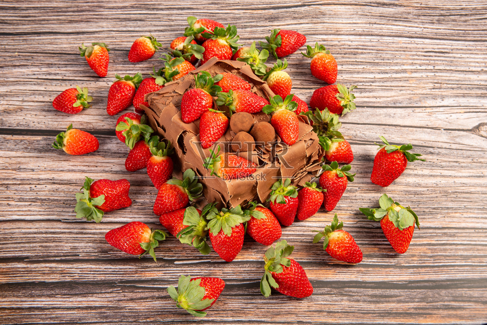 草莓巧克力蛋糕,香甜的巧克力蛋糕上覆盖着美味的草莓,放在质朴的木头上,选择性对焦。照片摄影图片