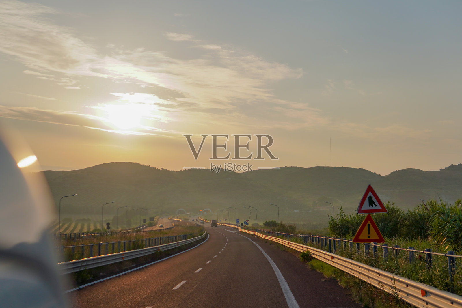 沿着意大利南部风景如画的高速公路行驶。郁郁葱葱的绿色山丘上点缀着整齐卷好的干草。道路的柔和曲线营造出一段电影般的旅程。照片摄影图片