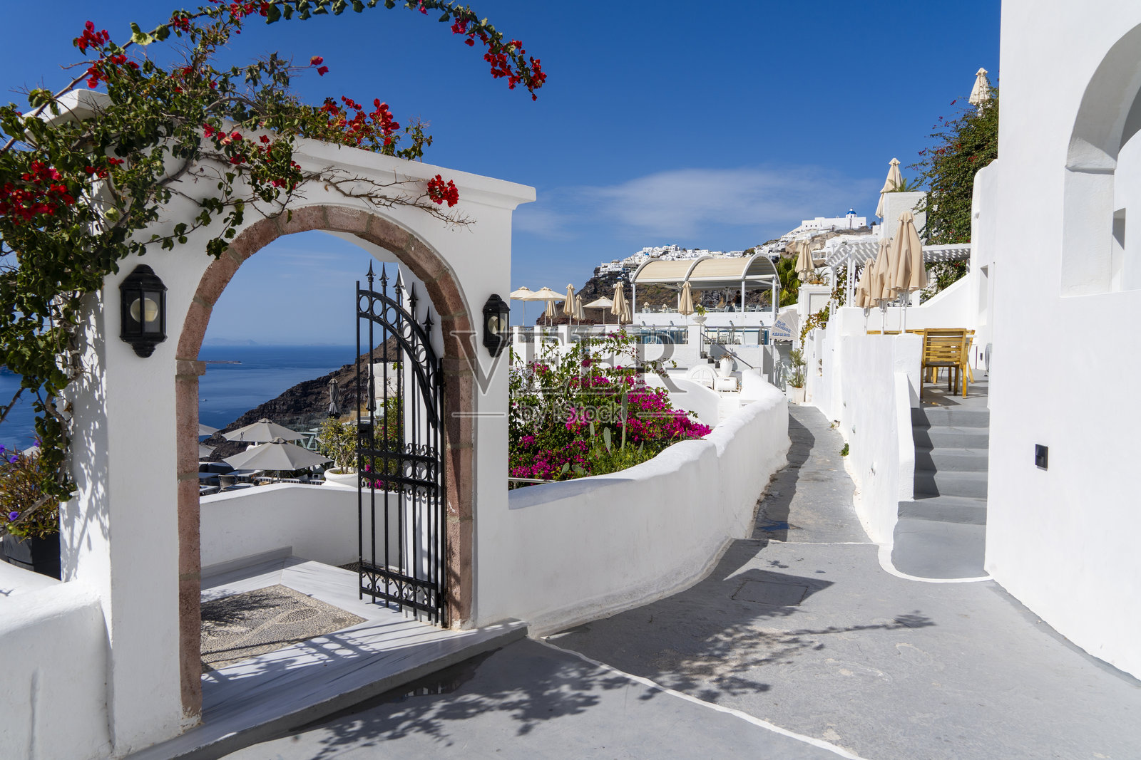 圣托里尼的拱门俯瞰火山口,拱门上覆盖着九重葛。照片摄影图片