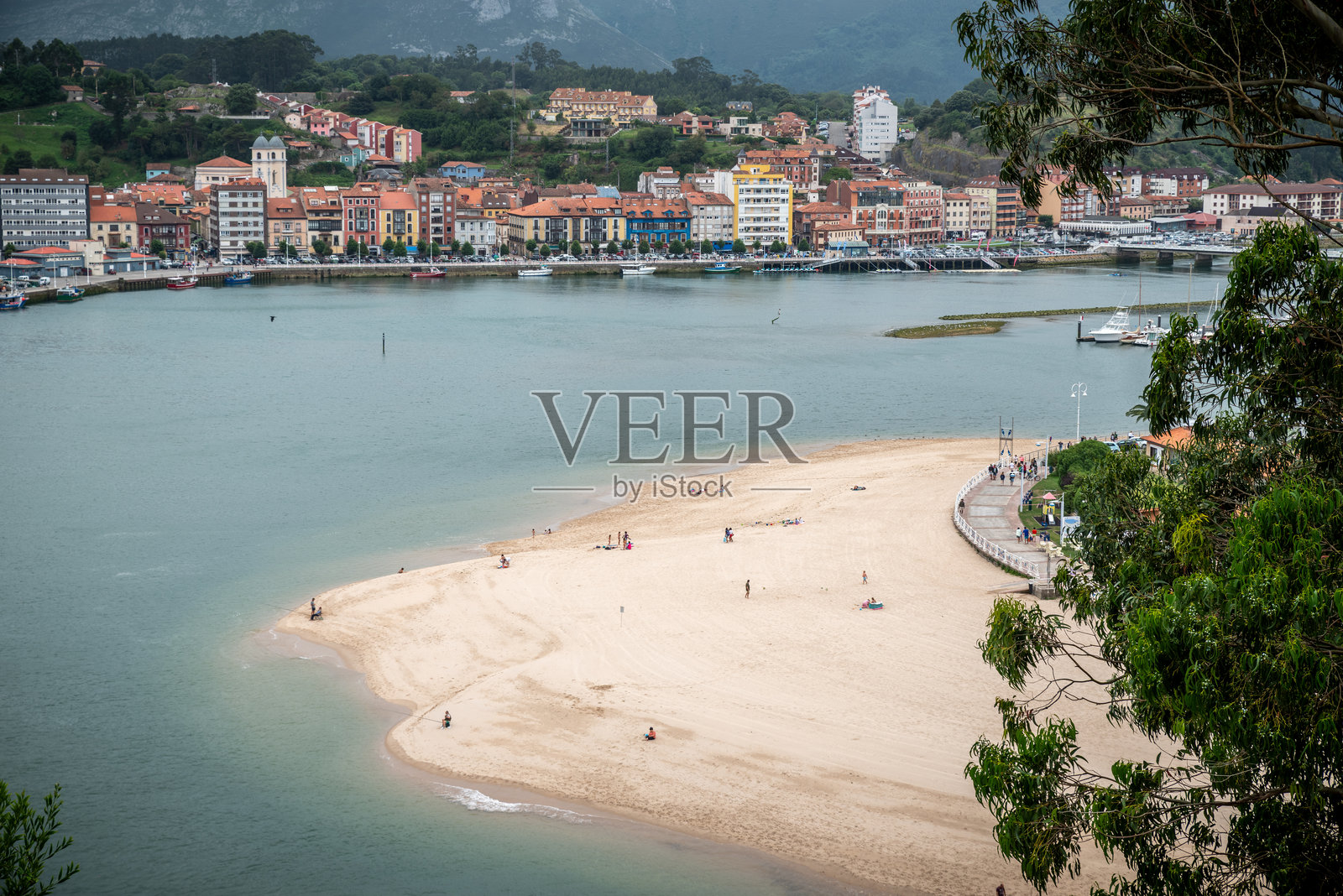 游客们在阿斯图里亚斯的里巴德塞利亚沙滩上晒太阳,享受温暖的阳光,周围是迷人的海岸风景。照片摄影图片