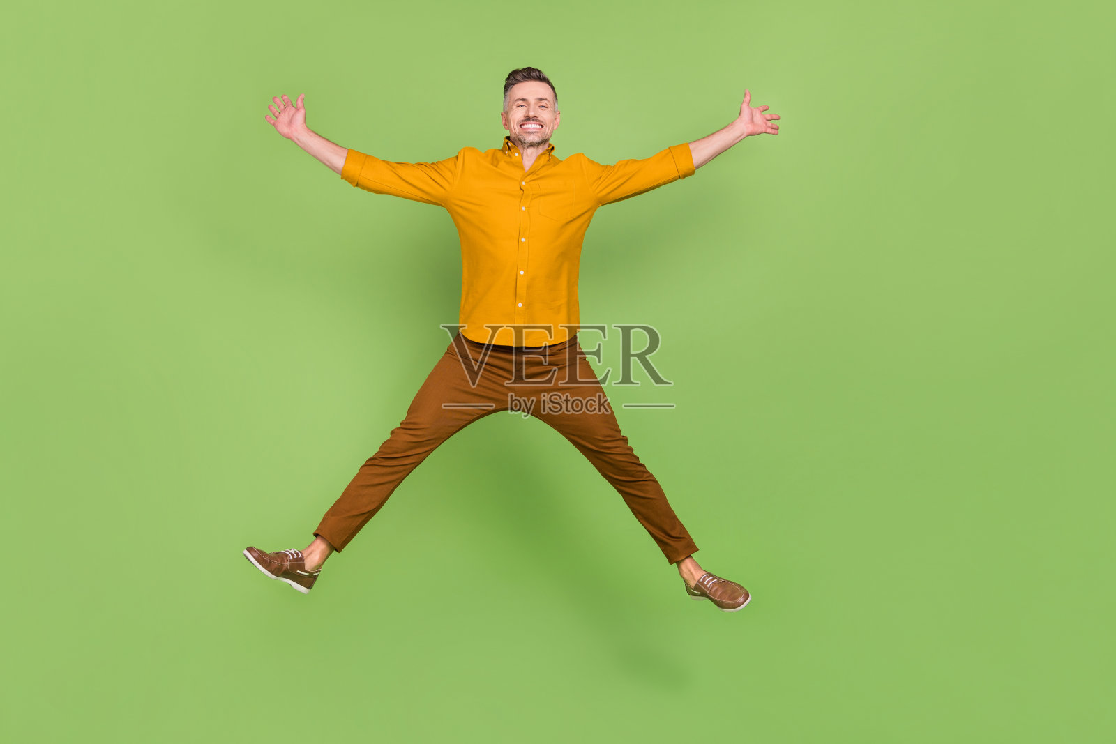 充满活力的成熟男性在绿色背景上兴奋地跳跃,享受乐趣的全身照片照片摄影图片