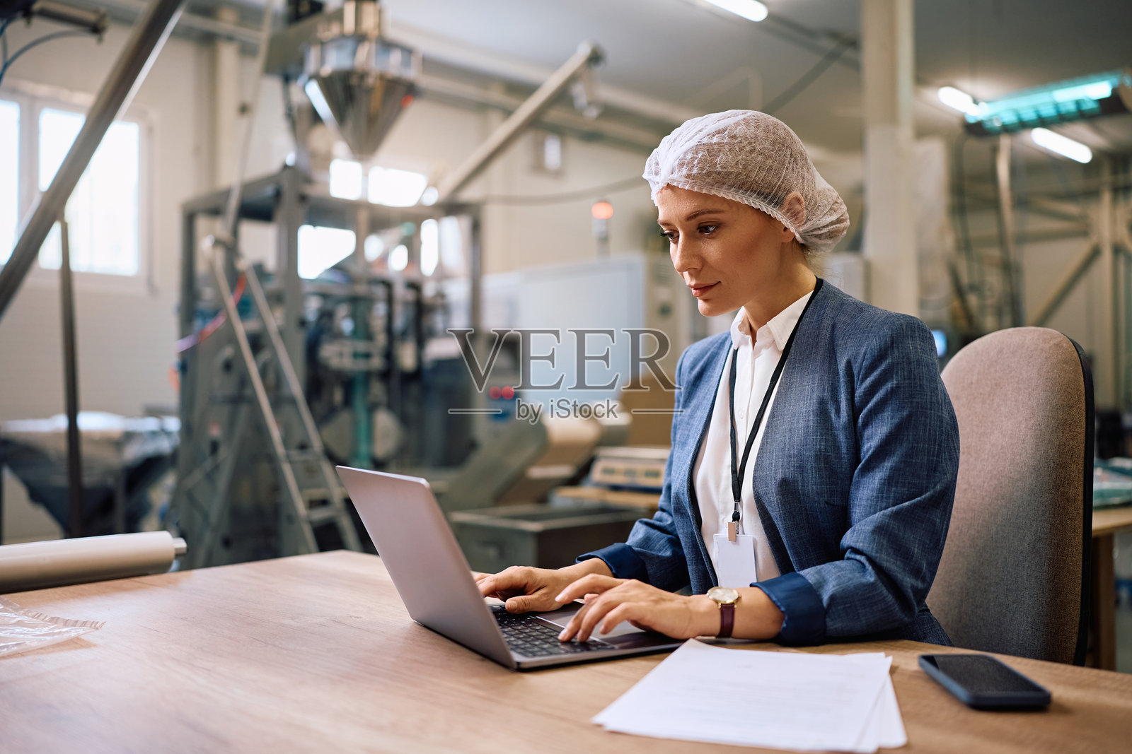 女公司经理在工厂内使用笔记本电脑工作。照片摄影图片