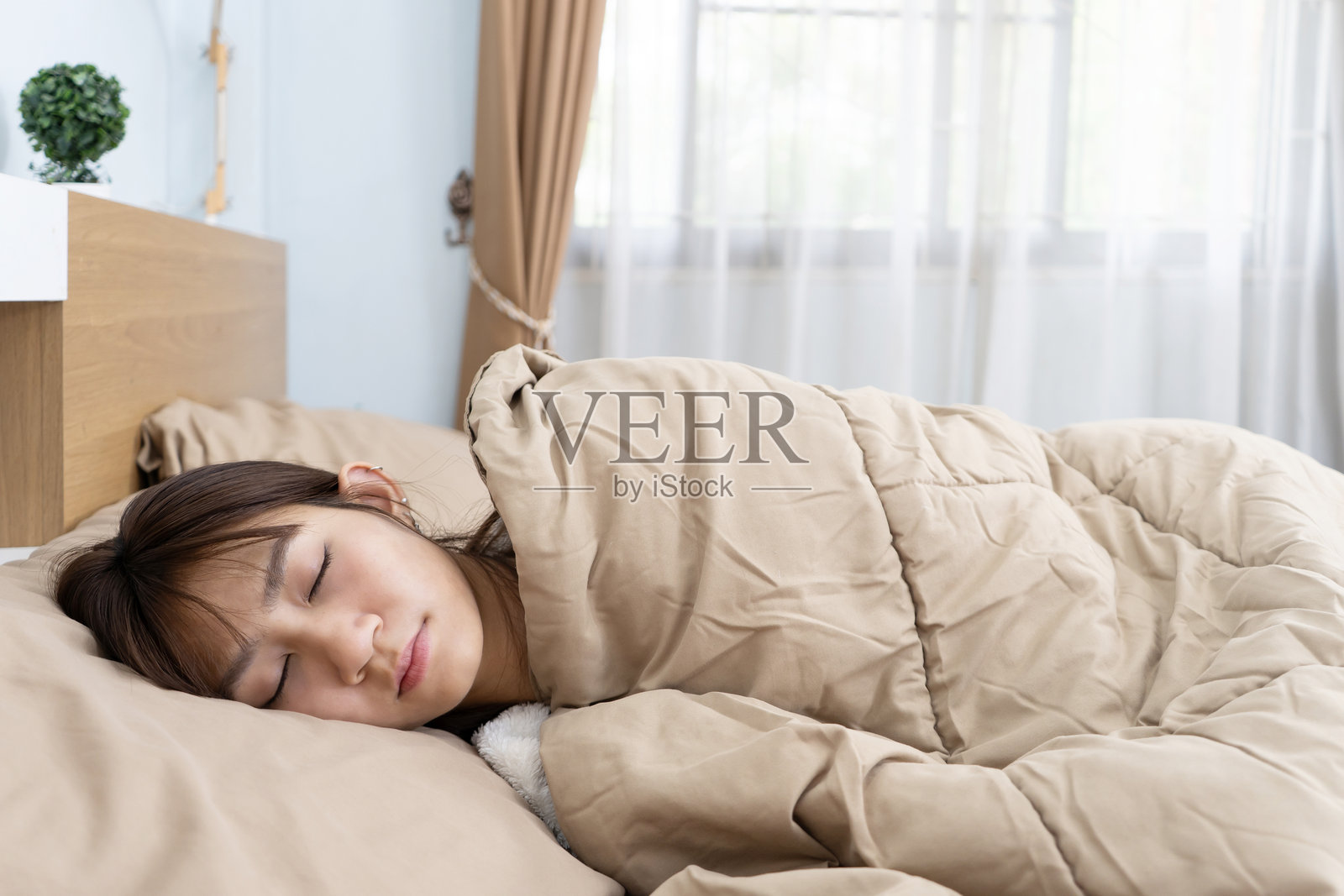 亚洲年轻可爱的女孩在床上盖着毯子睡觉照片摄影图片