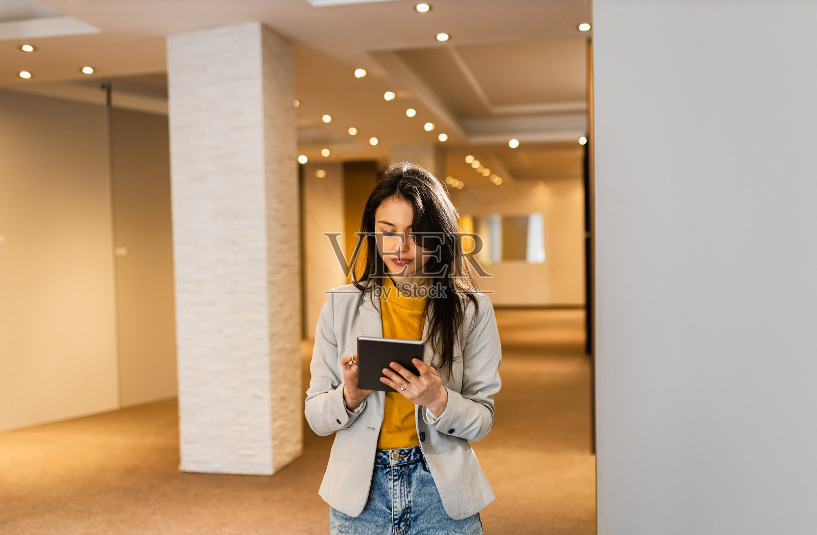 年轻女销售员在展厅中使用平板电脑的肖像。照片摄影图片