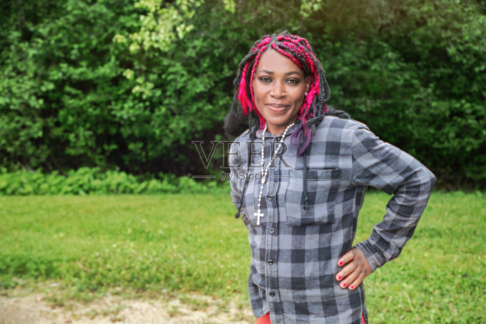 美丽的非裔美国女性,粉色盒子辫,背景为自然公园景色照片摄影图片