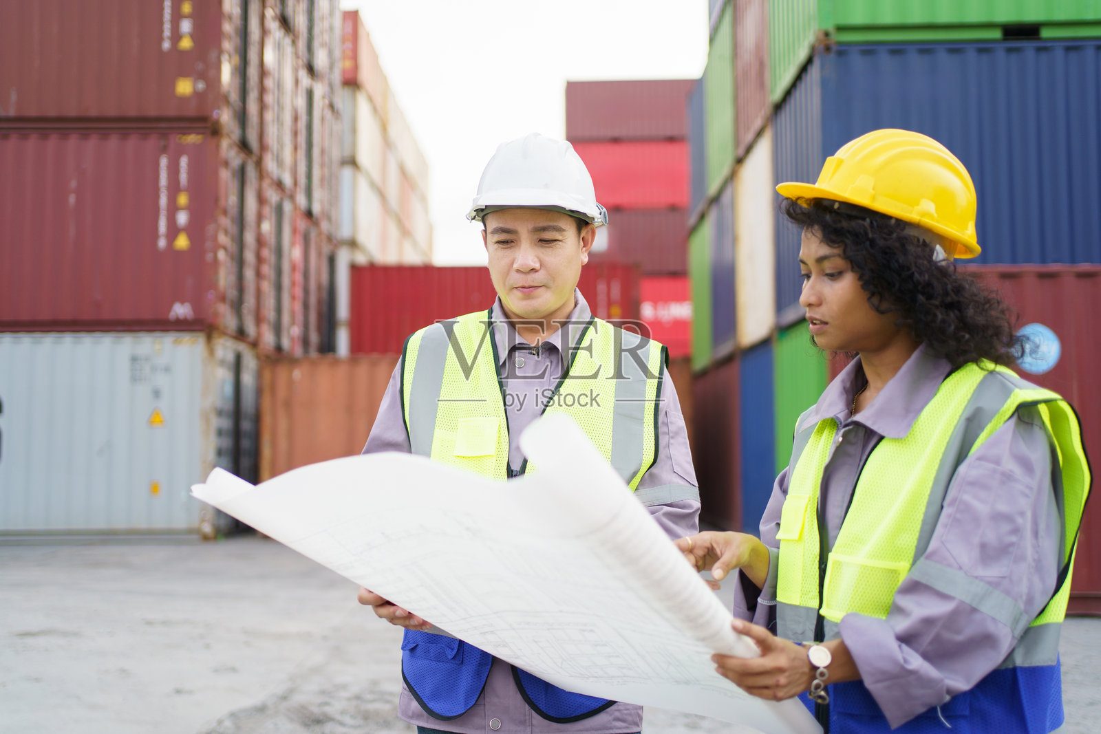 女商人与物流或船厂工程师在集装箱场进行讨论或商务洽谈。照片摄影图片