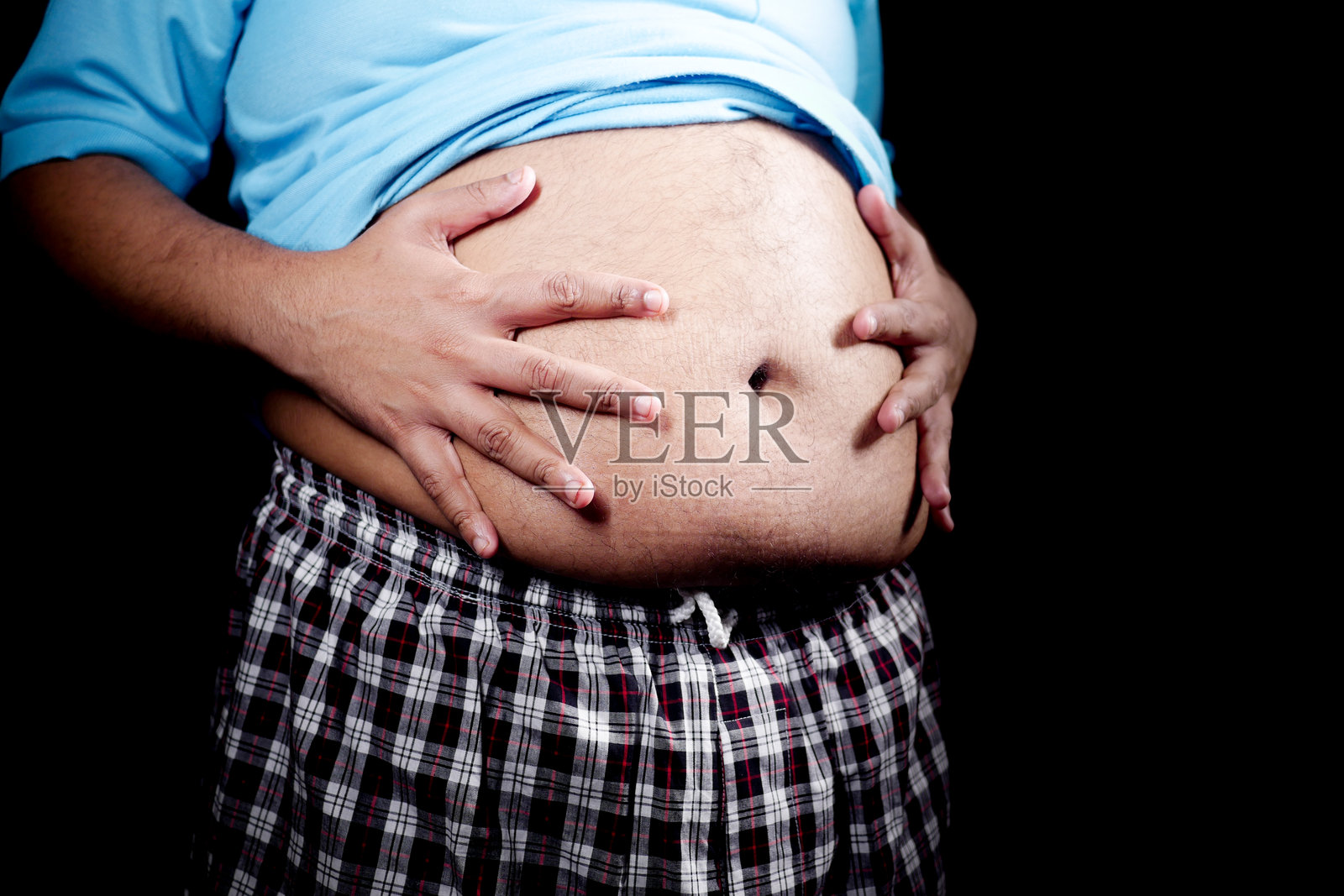 穿着蓝色衬衫的人在昏暗的环境中捂着肚子照片摄影图片