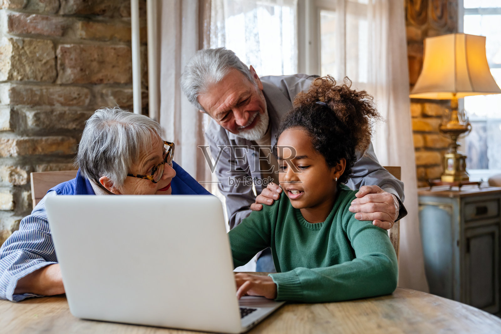 快乐的老年夫妇与孙子一起在家中使用现代科技设备笔记本电脑。照片摄影图片