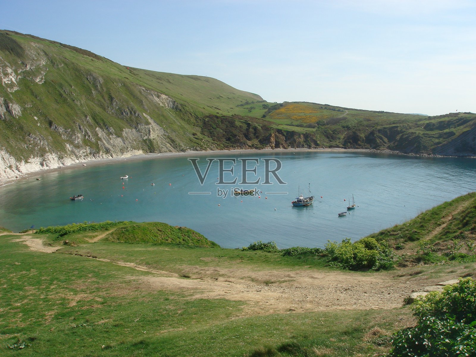 宁静的海湾,船只与郁郁葱葱的山丘在晴朗的夏空下照片摄影图片