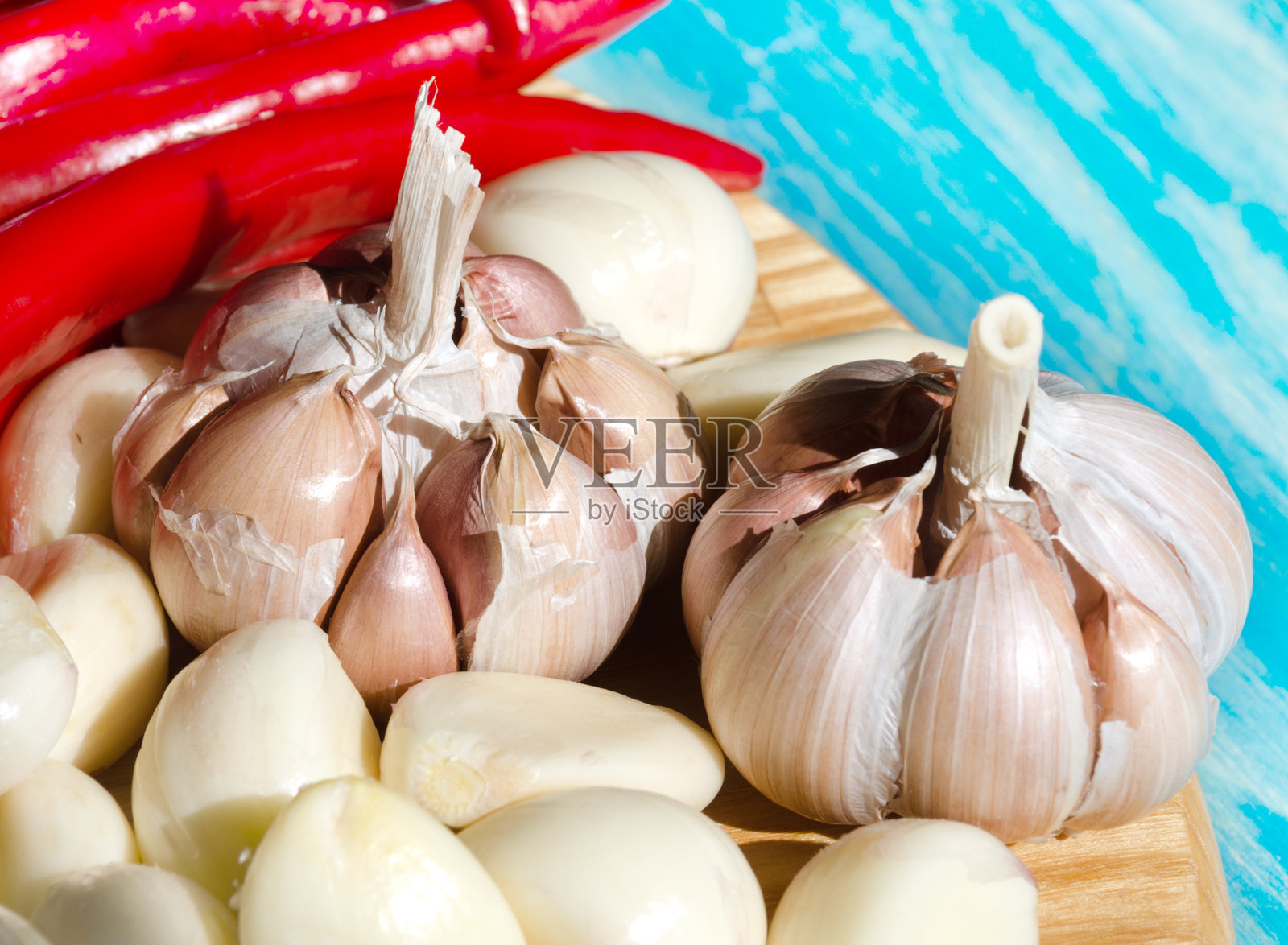 特写镜头下的精选大蒜,放在浅色木质表面上,背景为青绿色。照片摄影图片