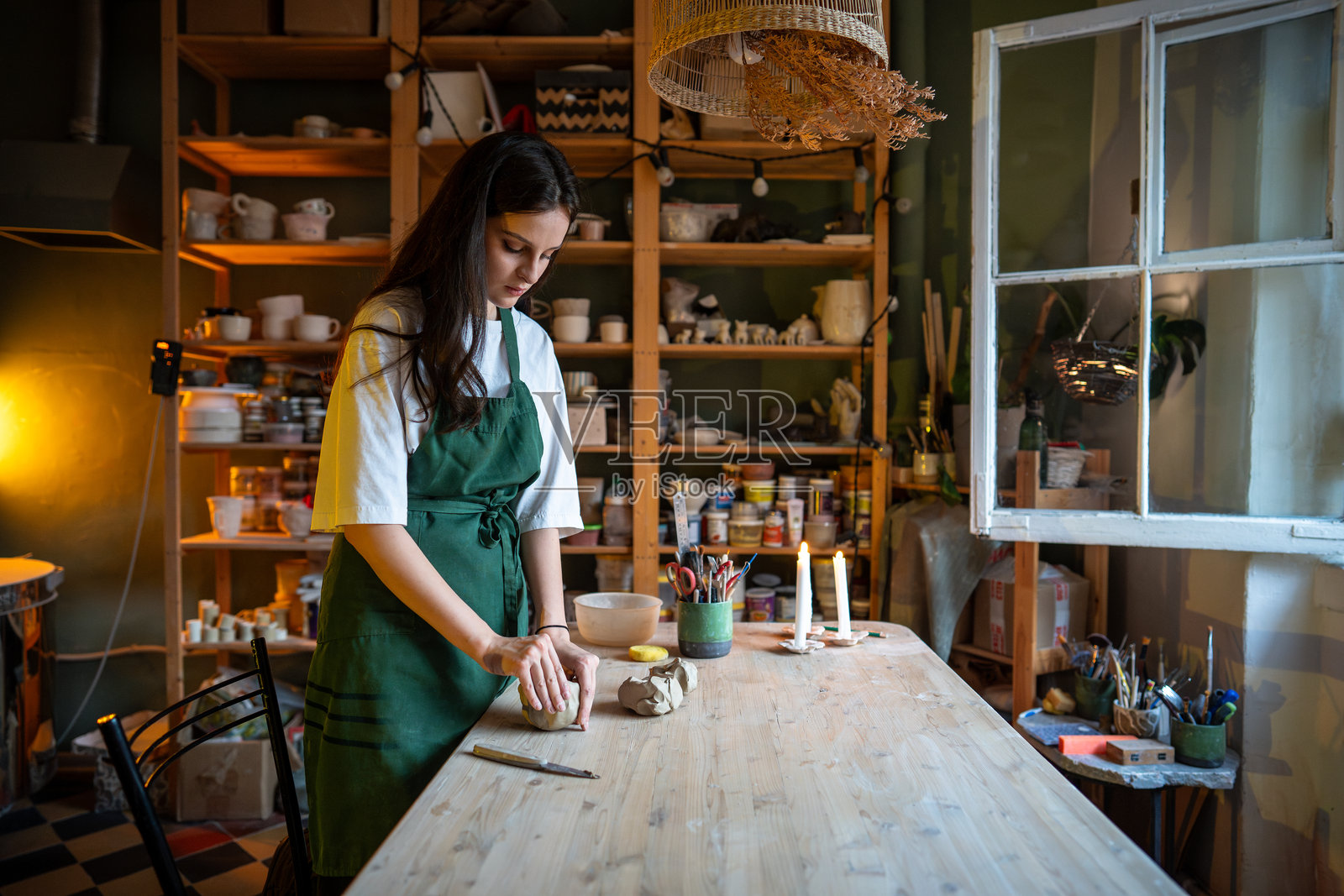 细心的女工匠在工作室准备粘土,以塑造陶器。自己动手的课程照片摄影图片