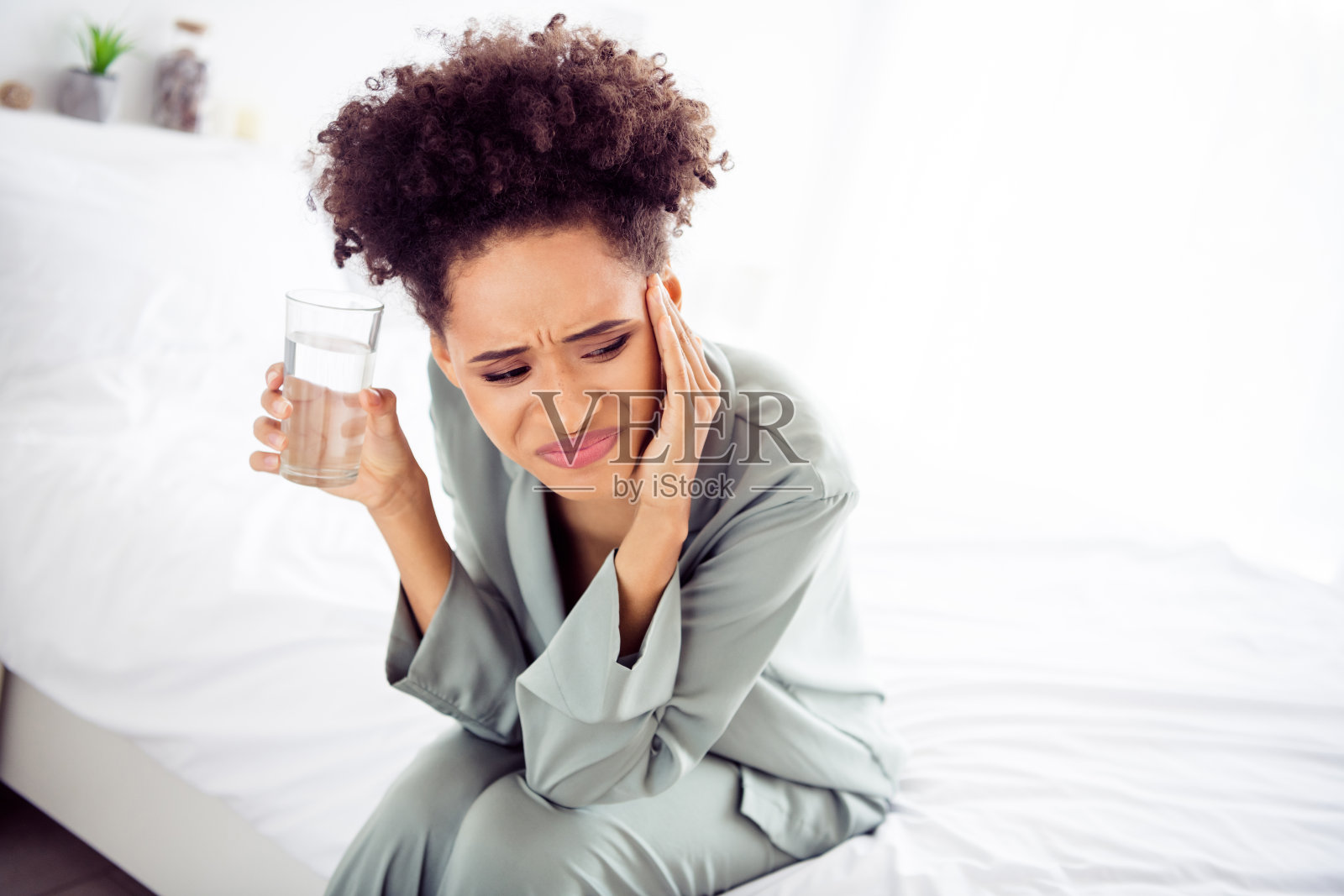 在室内的家中,一位迷人的抑郁女孩因慢性疾病而触摸太阳穴。照片摄影图片