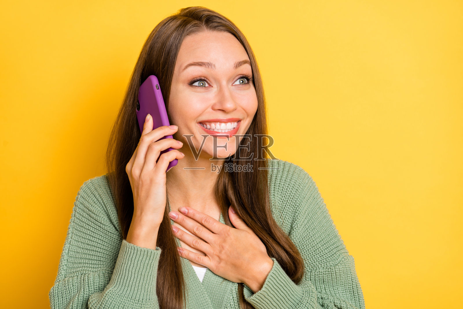 兴奋的女性触摸胸部,手持电话,背景为鲜艳的黄色,留有空白空间的照片肖像照片摄影图片