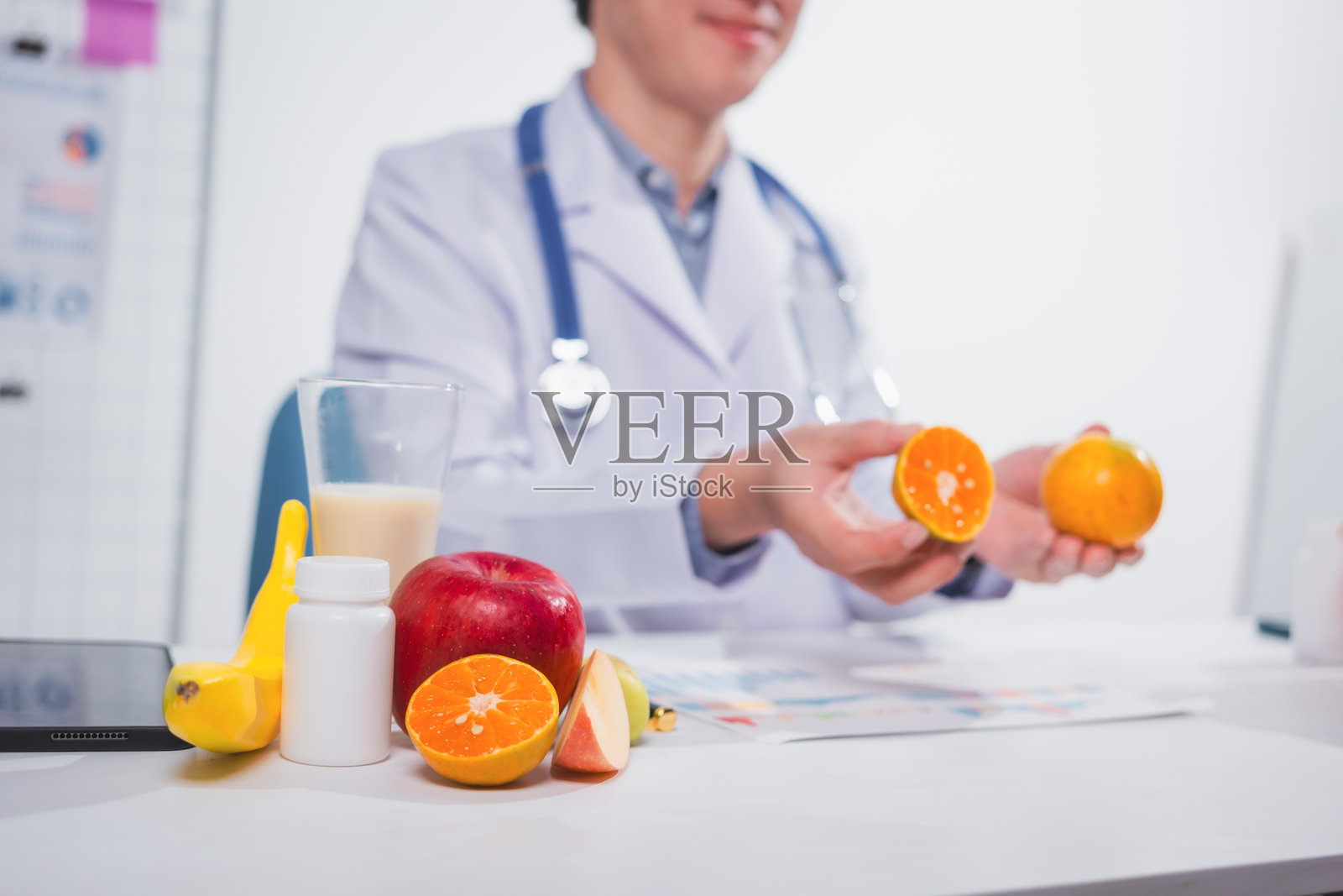 一位男性营养师在桌前工作,讨论吃水果的好处。他分析饮食并教育患者健康饮食习惯,以实现最佳健康和福祉。照片摄影图片