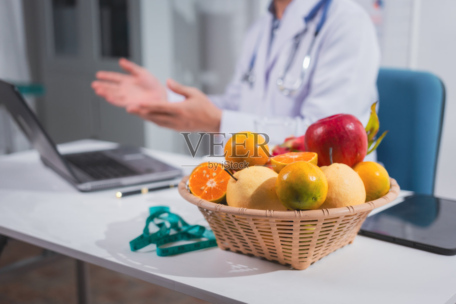 一位男性营养师在桌前工作,讨论吃水果的好处。他分析饮食并教育患者健康饮食习惯,以实现最佳健康和福祉。照片摄影图片