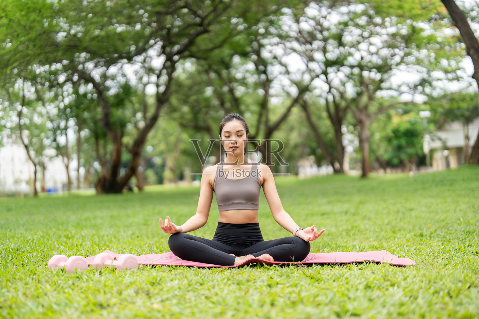 在大自然中练习瑜伽。年轻女性在户外的瑜伽垫上安静地冥想。照片摄影图片