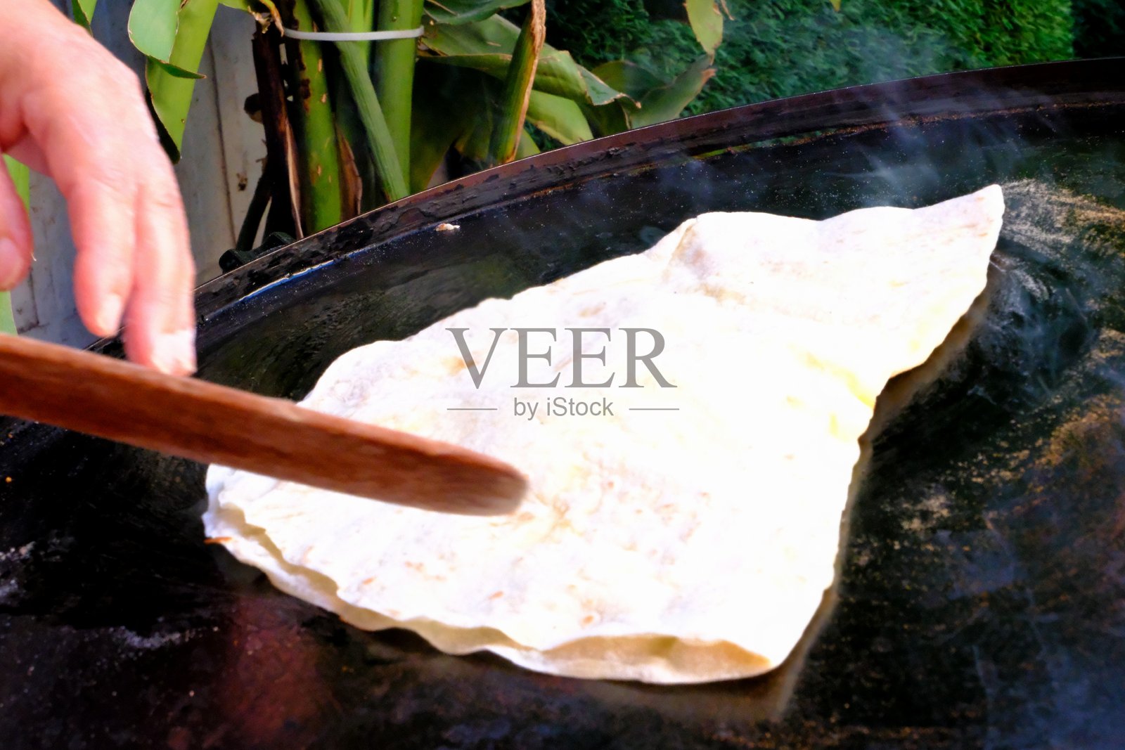 一位家庭主妇正在用擀面杖擀制传统土耳其美食 gözleme(一种扁面包),然后在烤盘上烹饪,最后呈现出来。照片摄影图片