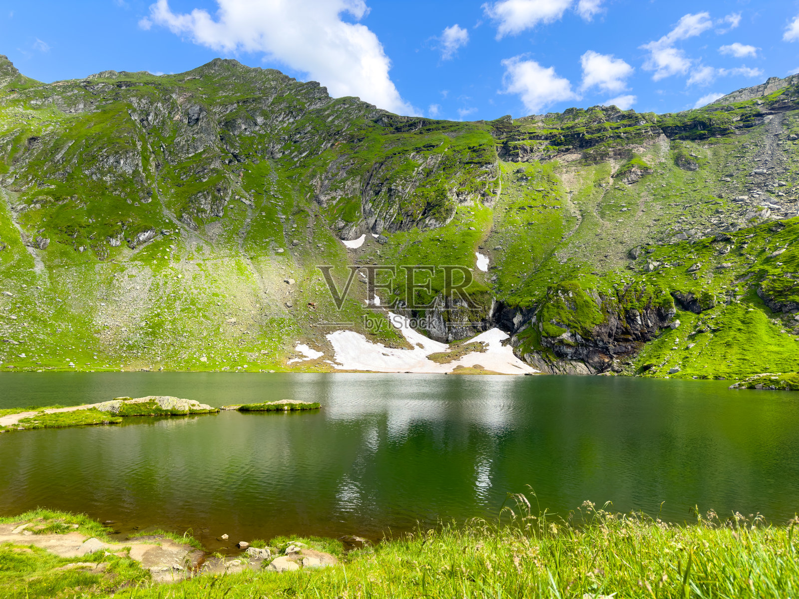 阳光明媚的日子里,风景如画的小湖被雄伟的山脉环绕照片摄影图片