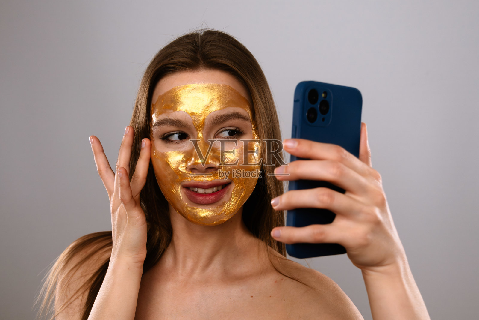 年轻女性涂抹金色面膜并自拍照片摄影图片